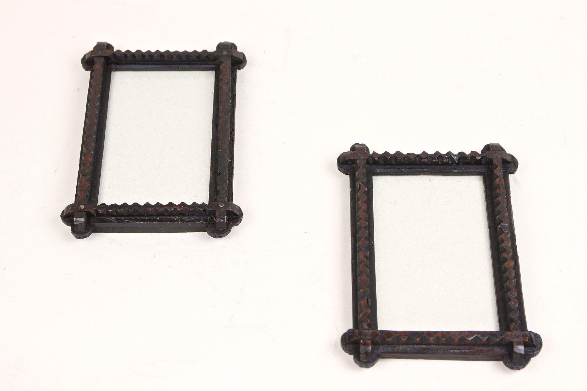 Dainty pair of rustic Tramp Art photo frames from the late 19th century, around 1860 in Austria. Elaborately hand carved out of bass wood this antique photo frames show a lovely design which the dark brown almost black stained surfaces reinforces.