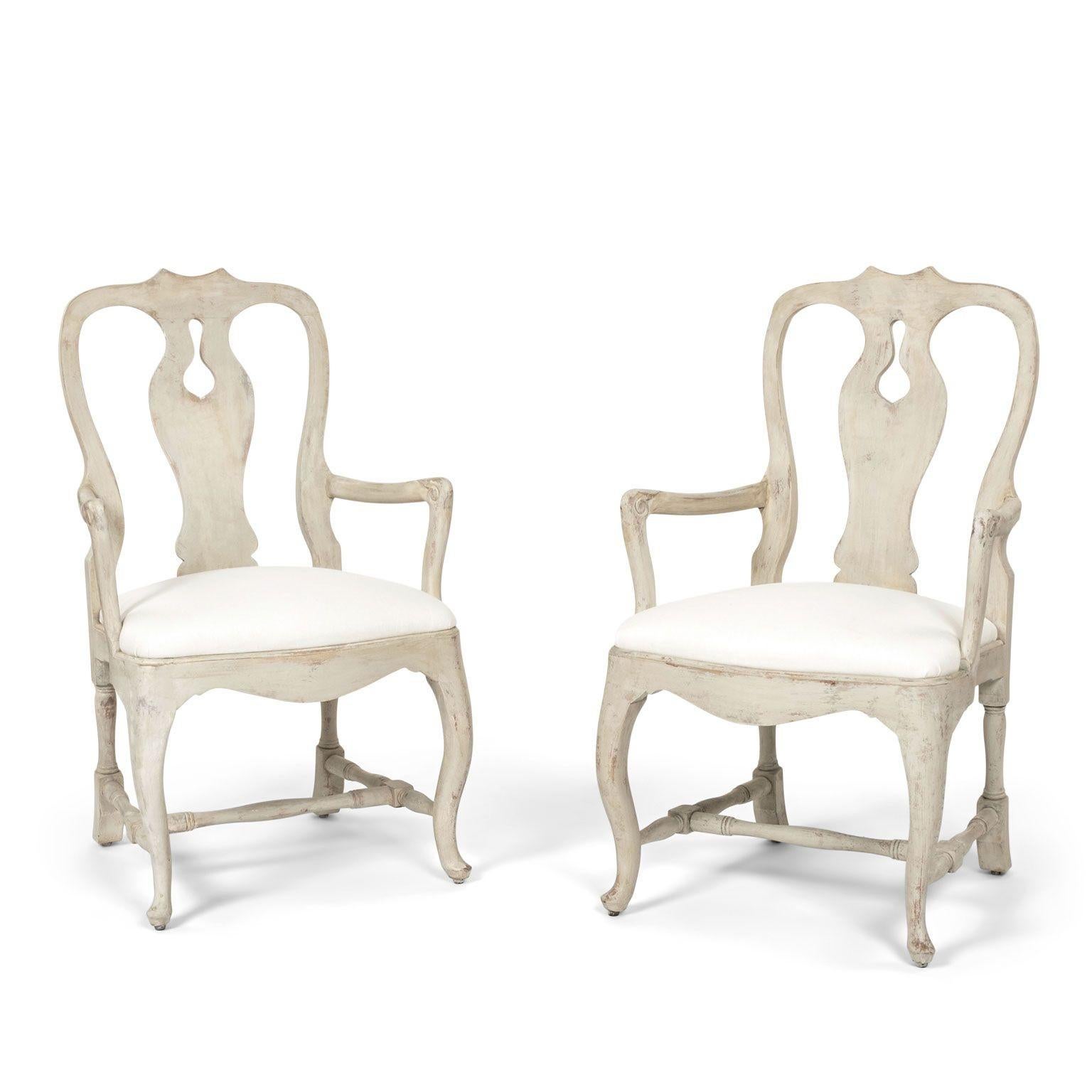 Pair of hand-carved vintage Swedish rococo style armchairs in off-white paint. Nice generous proportions, turned stretchers, pad feet and off-white color linen seats. Sold together and priced $3,600 as a pair.