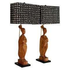 Paire de lampes figuratives d'art populaire africain en bois sculptées à la main et d'abat-jour tissés sur mesure