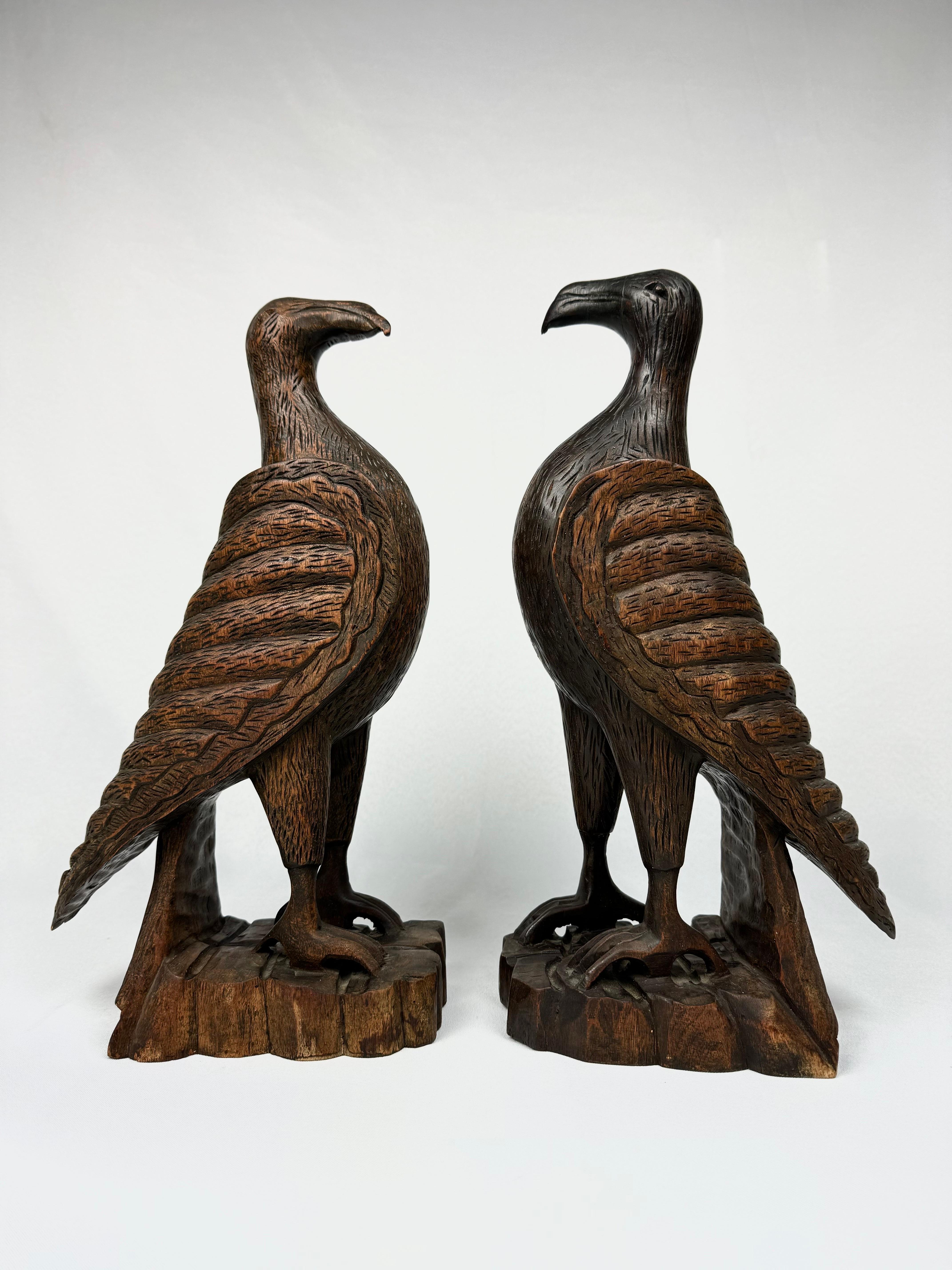 Paire de faucons en bois sculptés à la main. Créatures joliment sculptées avec des détails et une beauté étonnants. Parfait pour un amoureux des animaux, à placer sur un manteau ou une étagère.  Sculptures de style Black Forrest.