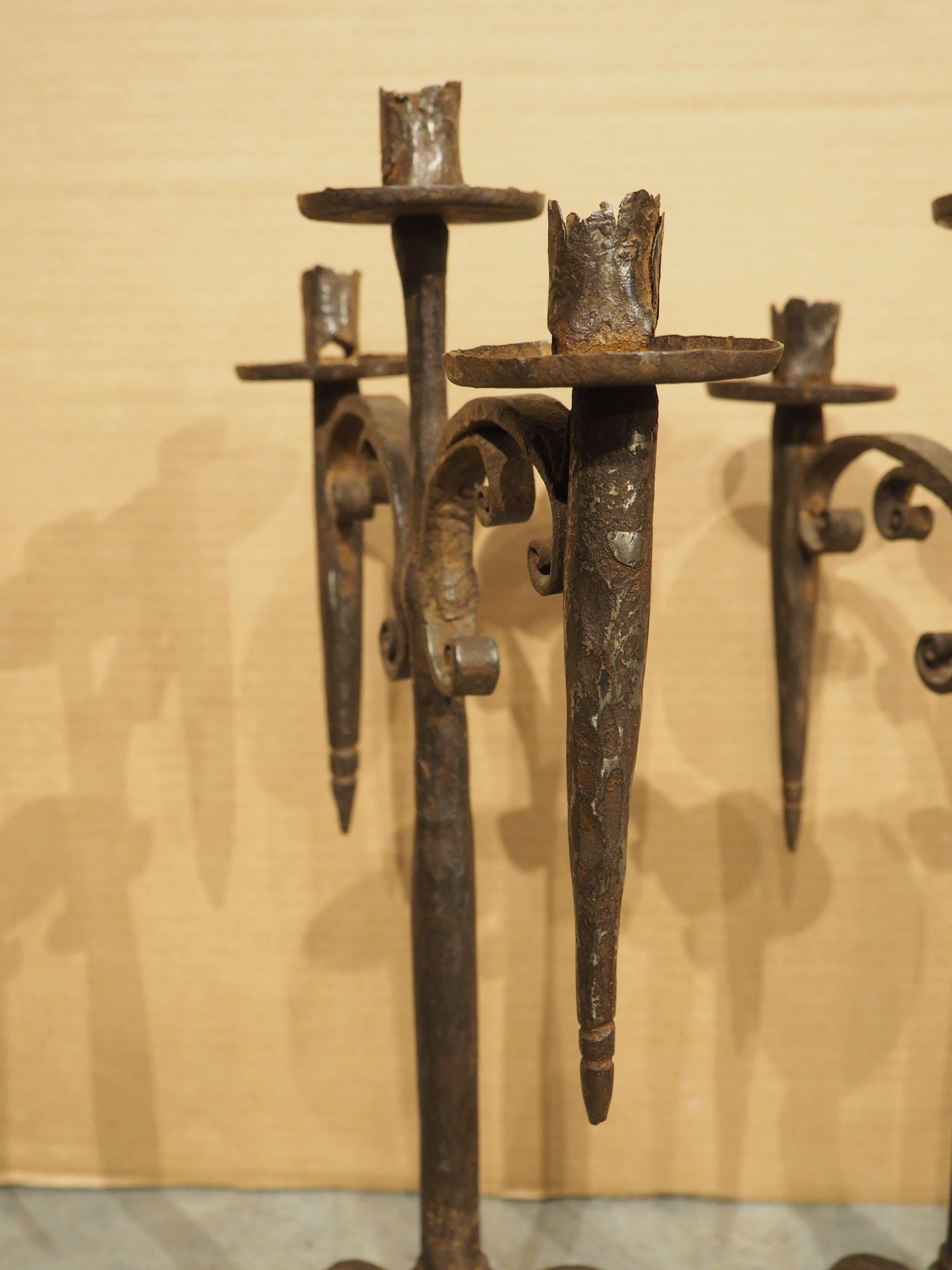 Dieses Paar eiserner Fackelkerzenhalter voller Charme und Charakter wurde um 1700 in Spanien handgeschmiedet. Die sichtbaren Schlagspuren des Schmieds sowie der abgeflachte Stift, mit dem die stark verschnörkelten Arme befestigt sind, verleihen den