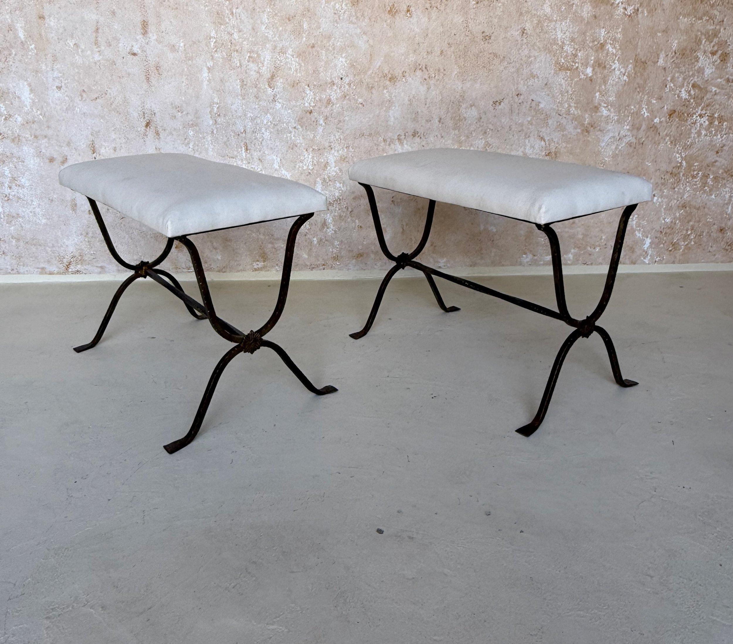 This elegant pair of Spanish gilt iron benches was recently handcrafted by skilled artisans using traditional iron working methods and materials. The hand forged, hammered frames feature slightly twisted stretchers with decorative rosettes at the