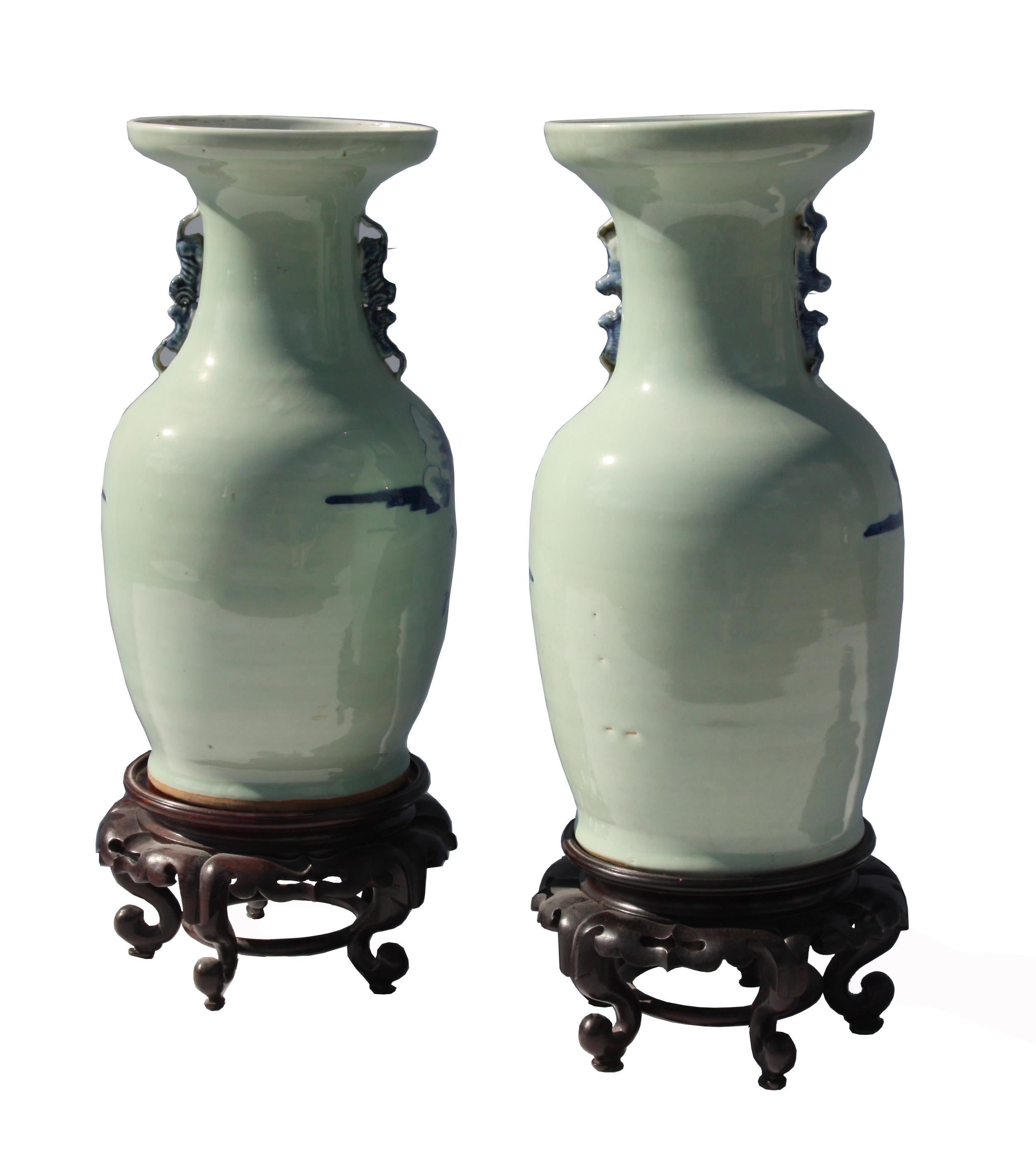 Two celadon vases decorated with five horses amidst rocks and trees. The vases are also embellished with two stylized handles resembling dogs at the base of the trumpet neck.
