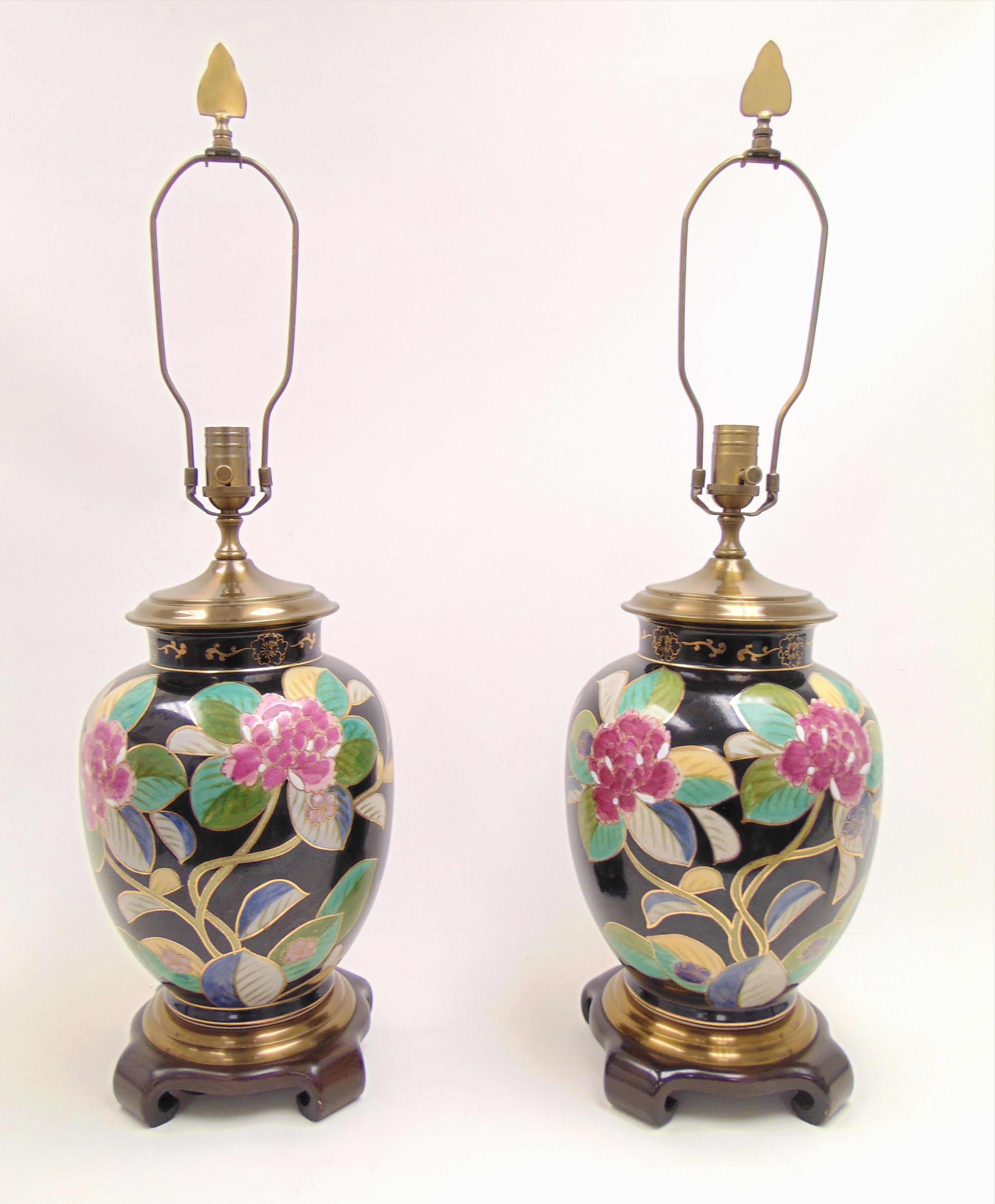 These are a beautiful pair of ceramic lamps from the 1980s by Wildwood Lamps. The flowers are hand painted with gold accents and set in a crackle glaze finish. The lamps sit atop wooden bases with scroll.