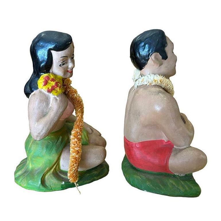 La Pareja de Figuritas de Cerámica Japonesas de Recuerdo de Chica Hula y Chico Ukelele Pintadas a Mano de los años 40 son objetos de colección vintage que capturan el encanto de la cultura hawaiana de mediados de siglo. Ambas figuras están sentadas