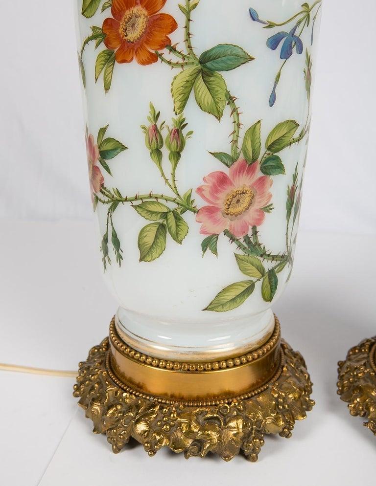 We are pleased to offer this pair of exquisite opaline vases now made into newly electrified lamps. The lamps are decorated all around with beautiful hand painted roses on the stem, along with their leaves and rosebuds. The roses on their stems wind