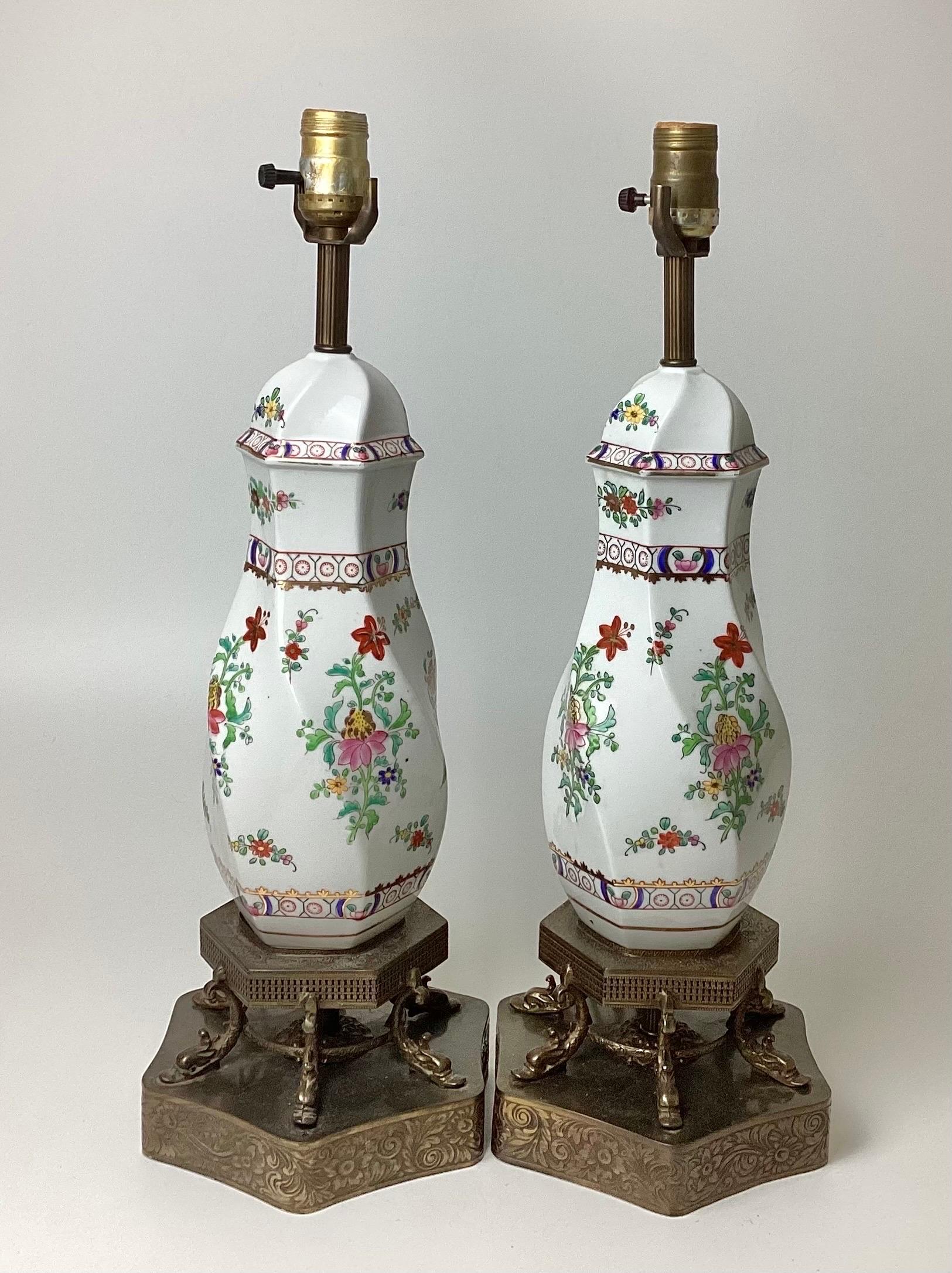 Pair of hand-painted porcelain lamps white with flowers on filagree brass dolphin bases. Stand 21