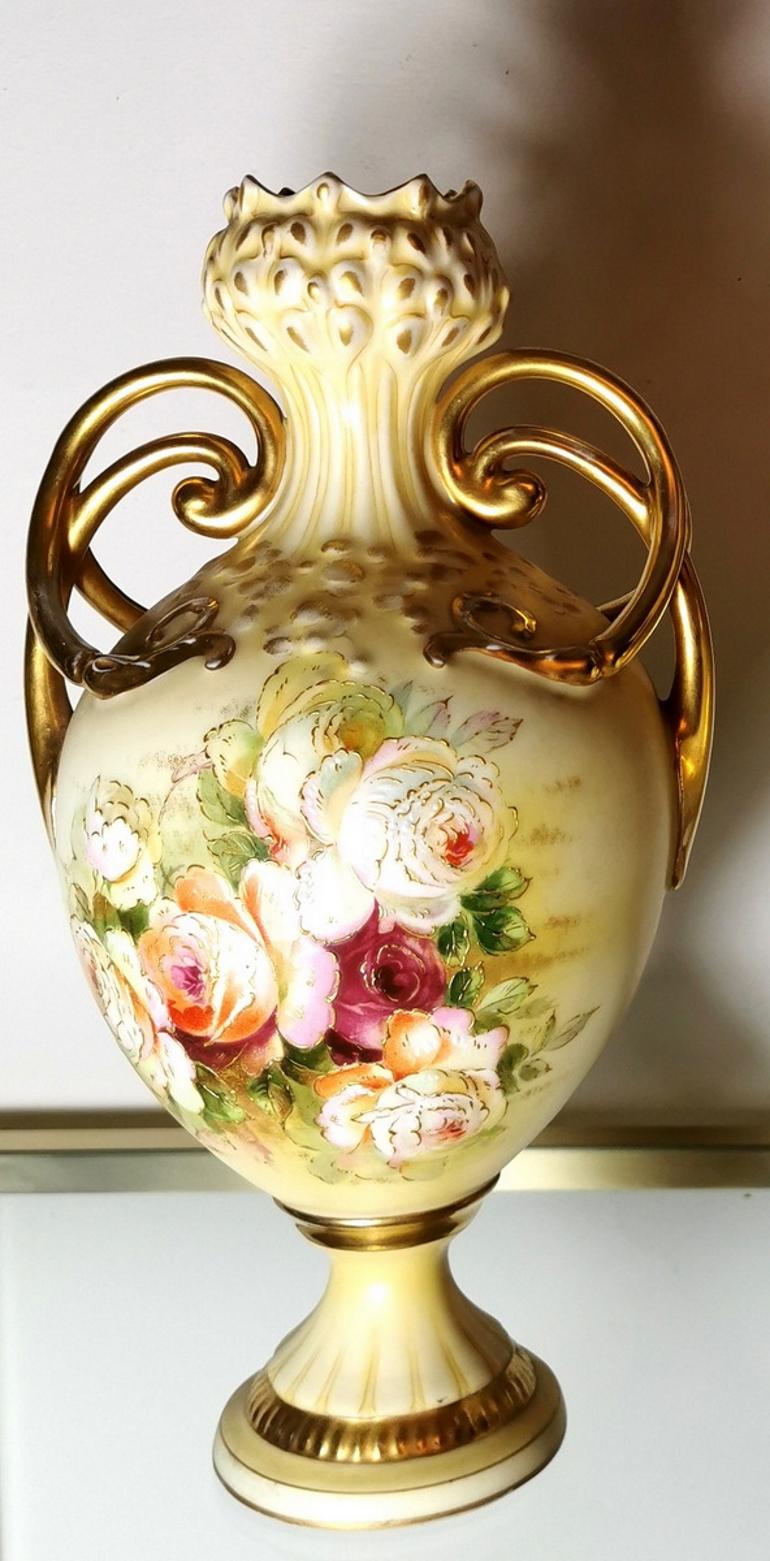  A pair of French porcelain vases with beautiful floral decorations; the roses are hand-painted with delicate colors, soft shades, and finished with light gold strokes on the edges of the petals; very particular and showy are the three-wire handles