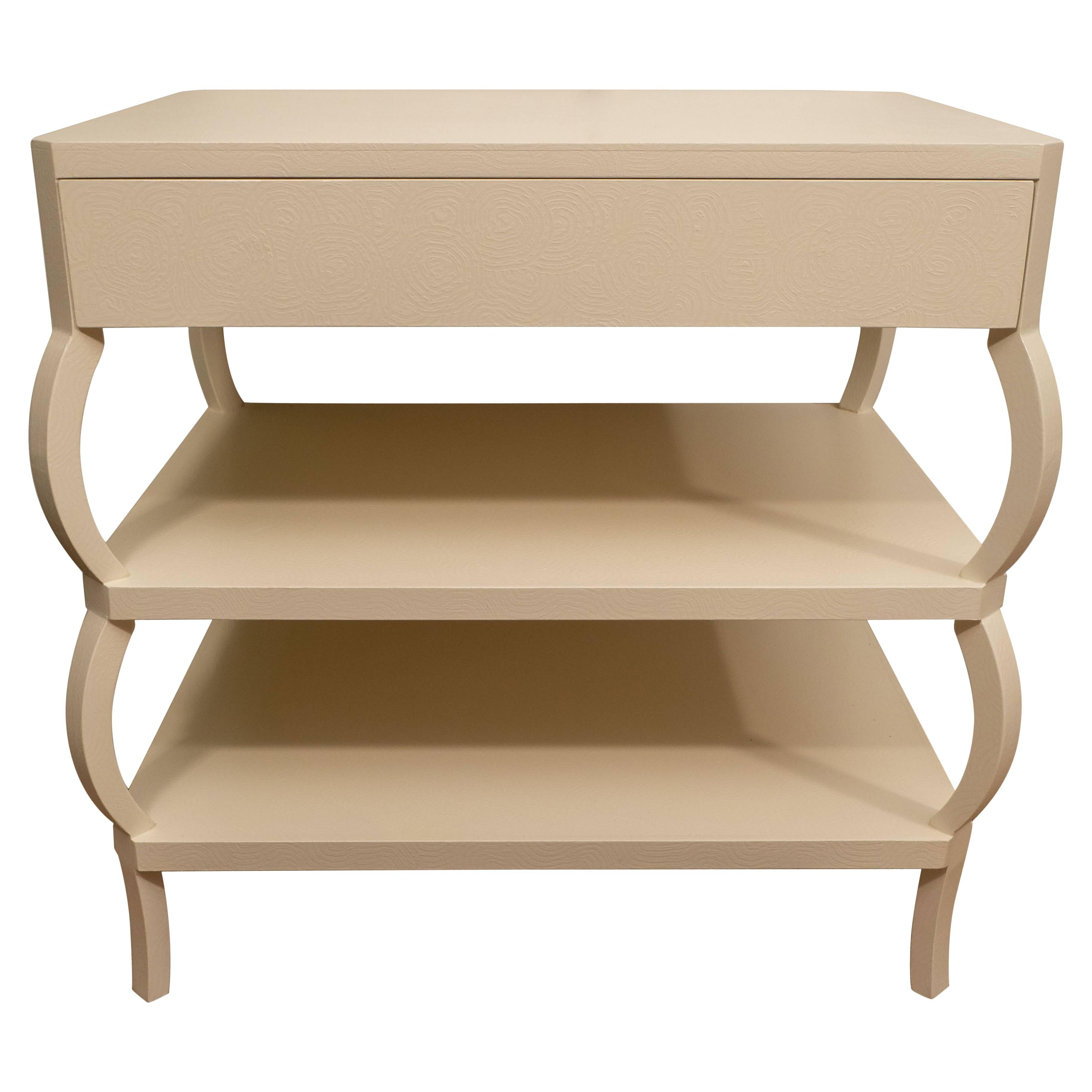 Perfect for night tables or for flanking a sofa, these tables feature a top drawer and two lower shelves. They have been painted by hand in a cream color with a subtle “swirl” design.