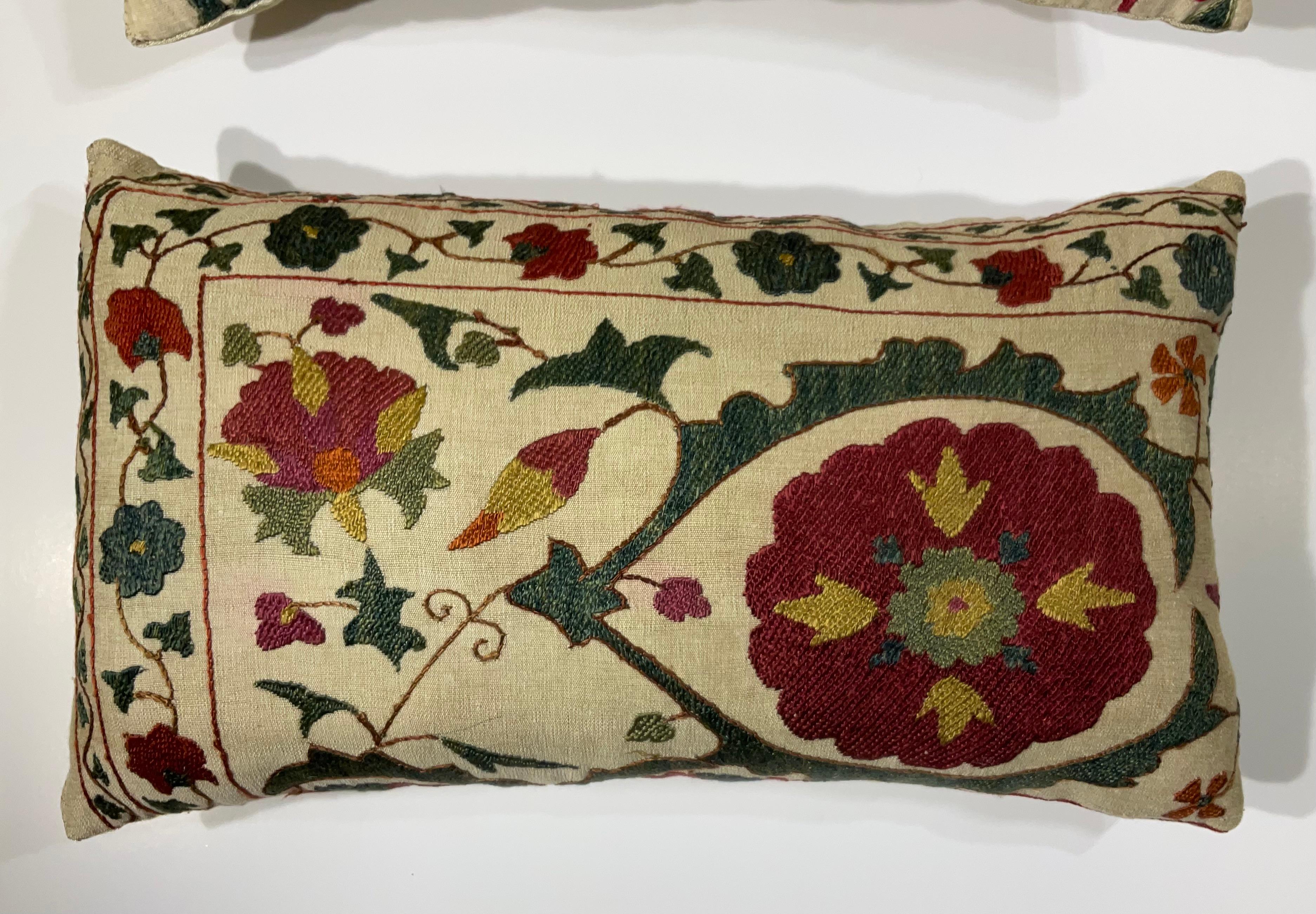 coppia di cuscini vintage con ricamo Suzani. Questi cuscini sono una vera e propria testimonianza della ricca storia e dell'intricata arte dei tessuti dell'Asia centrale. Realizzato a mano da abili artigiani, ogni cuscino presenta un motivo floreale