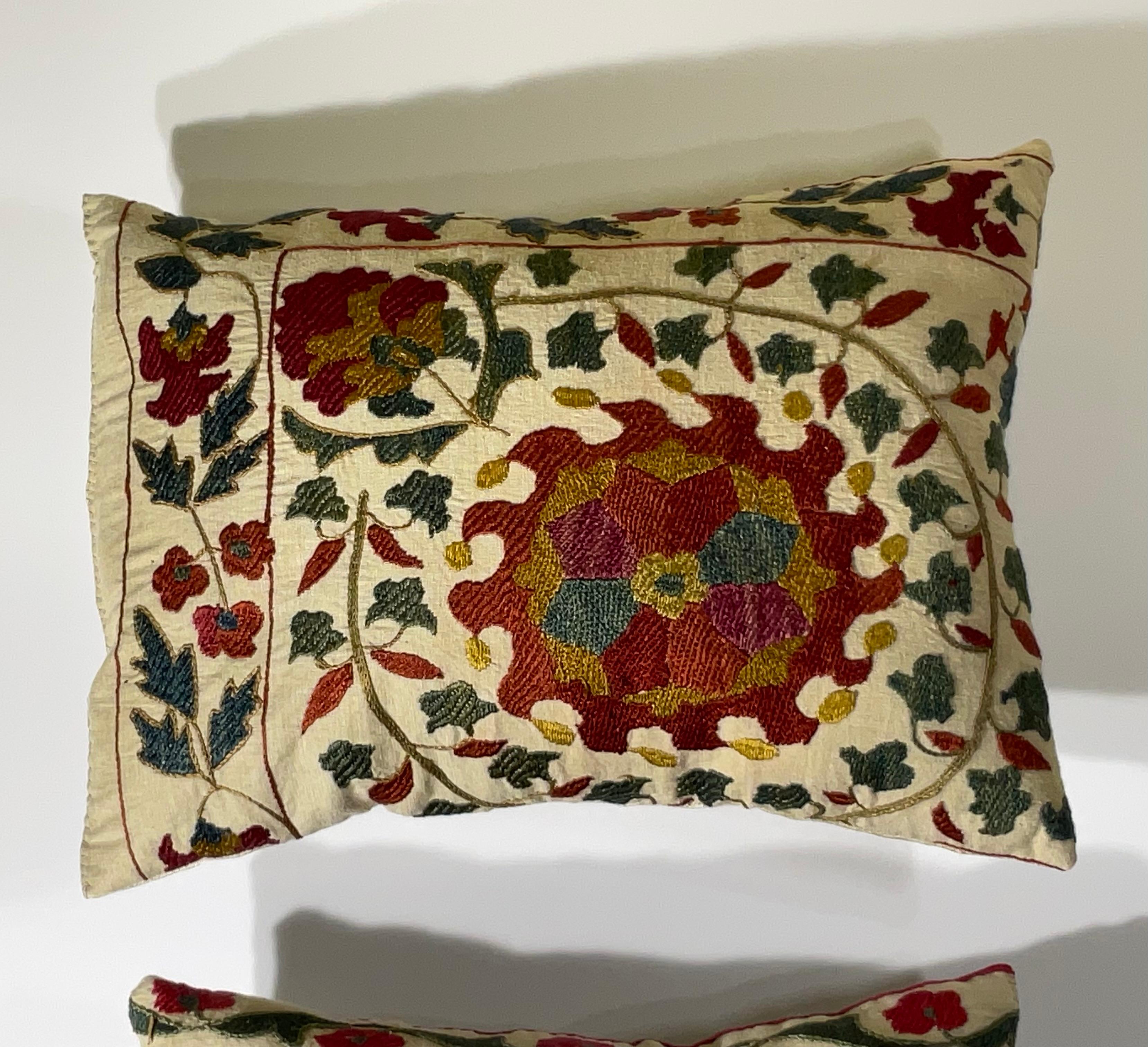 pair of vintage Suzani embroidery pillows. These pillows are a true testament to the rich history and intricate artistry of Central Asian textiles. Handcrafted by skilled artisans, each pillow features a unique, vibrant floral motif, characteristic