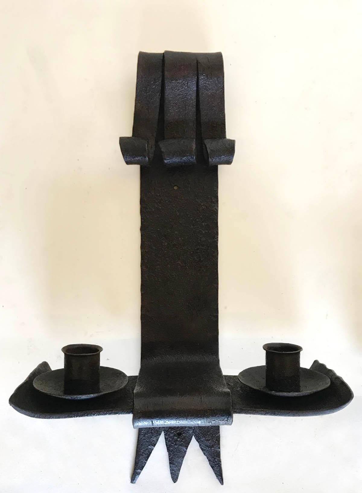 Pair of handwrought iron sconces with two arms each. You can place a candle or have them electrified. Dark patina. Strong profile.
