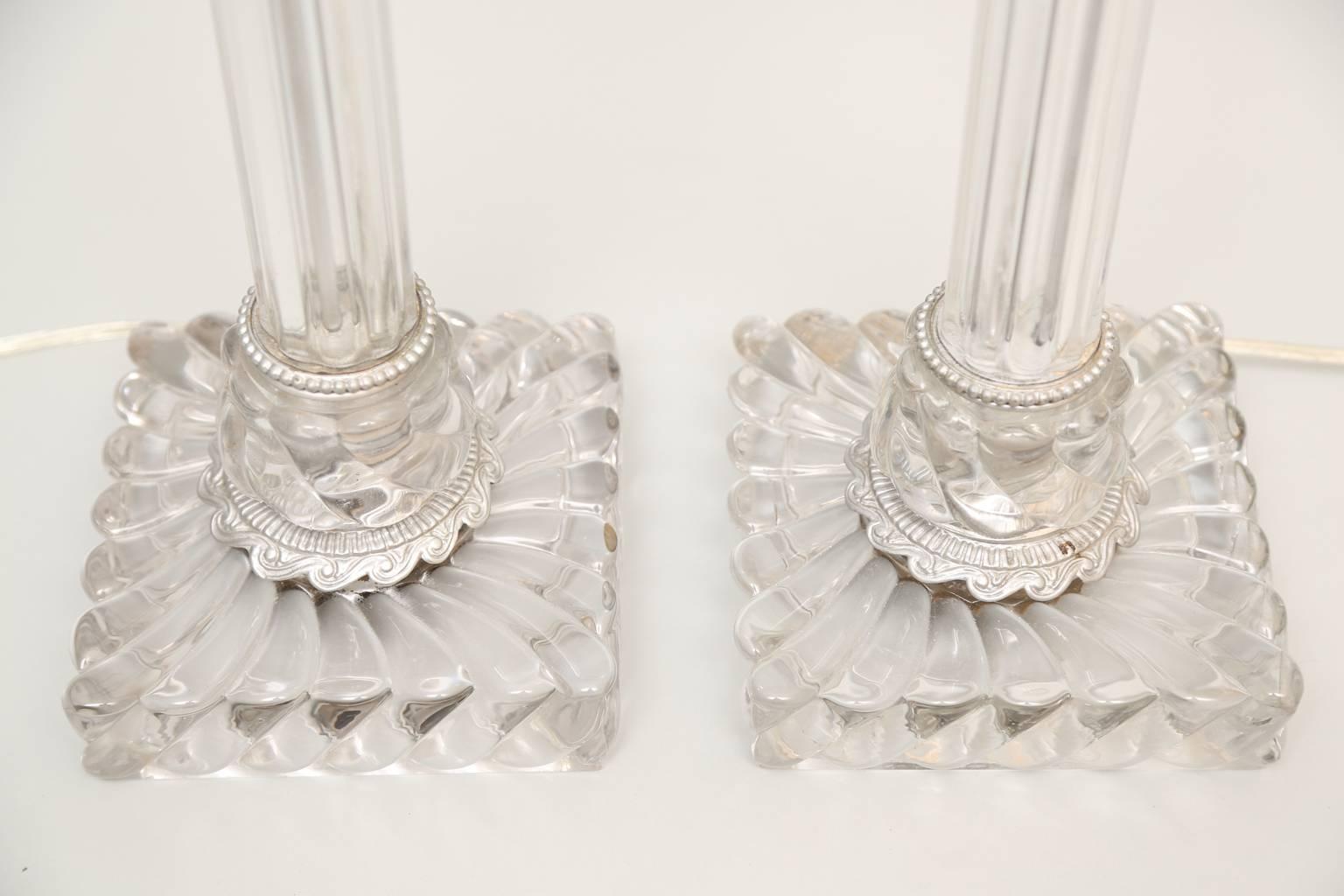Pair of lamps by Baccarat, originally oil burning, each a handblown fluted glass column raised on square swirling glass base; silver giltwood base and fittings.