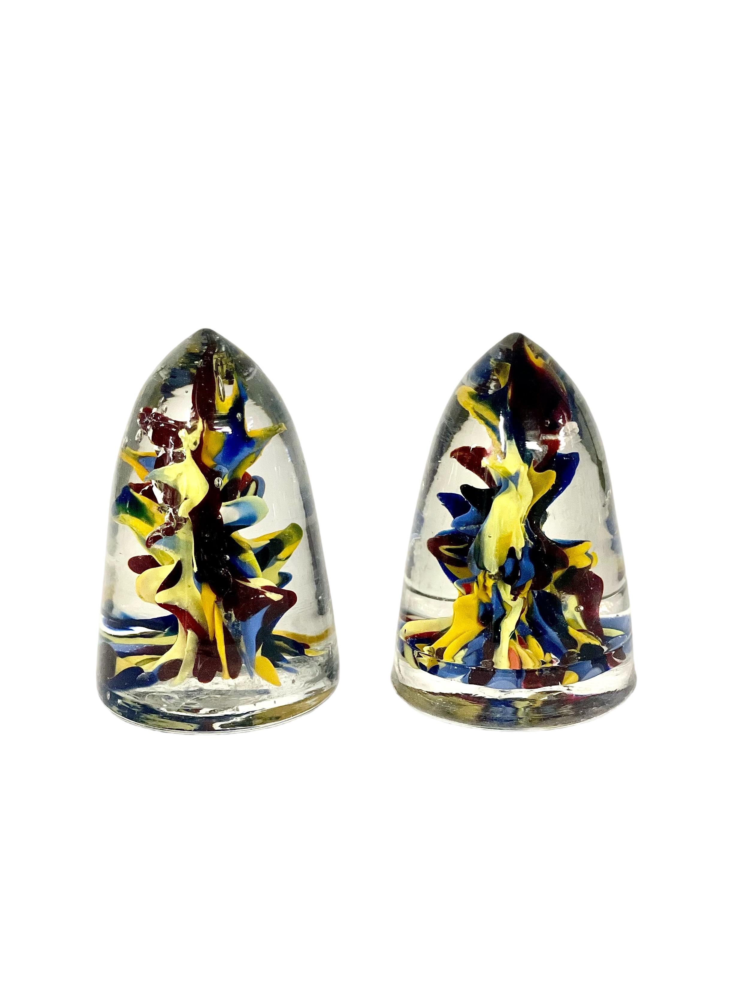 A very unusual and eye-catching pair of 19th century crystal paperweights in the shape of conical 'shells'. Smooth to the touch, their clear crystal cones are filled with a riot of hand blown colours in vibrant shades of blue, yellow and red.