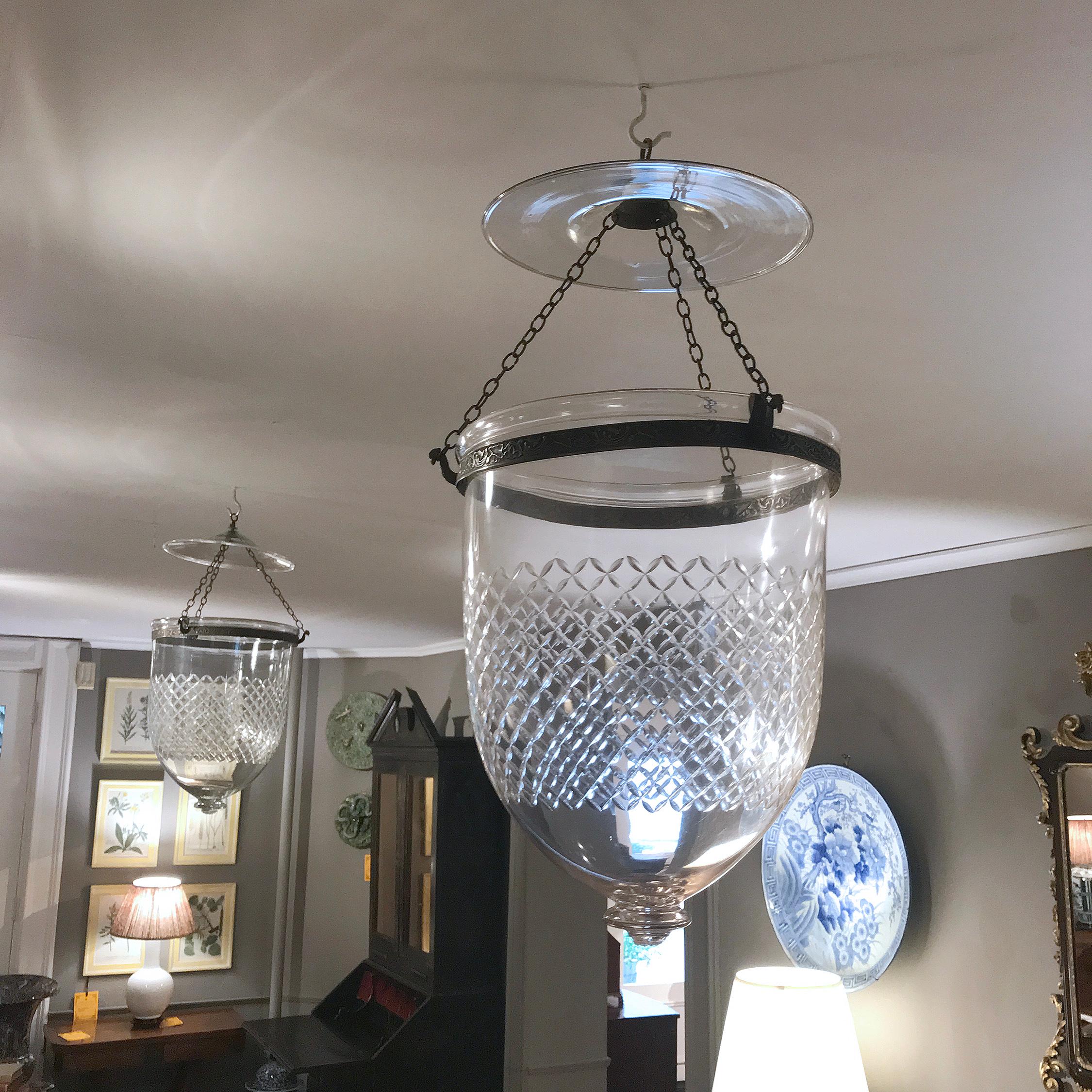 Each of these beautiful 19th century handblown glass bell jar lanterns is ornamented with an etched diamond motif. Three chains from the glass smoke bell and brass canopy attach to peacock-shaped hooks on the original rolled brass band, supporting