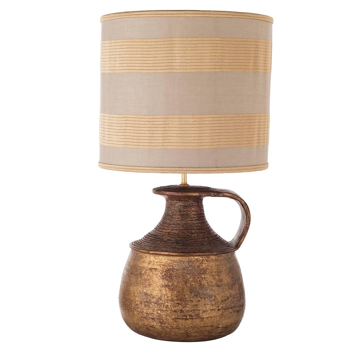 Pair of rustic terracotta table lamps featured by a handle vase-shaped body. Ceramic is skillfully gold and rusty-brown decorated, wonderfully matched with a cylindrical rich shade, striped in gathered gold and off-white fabric. Wired to your