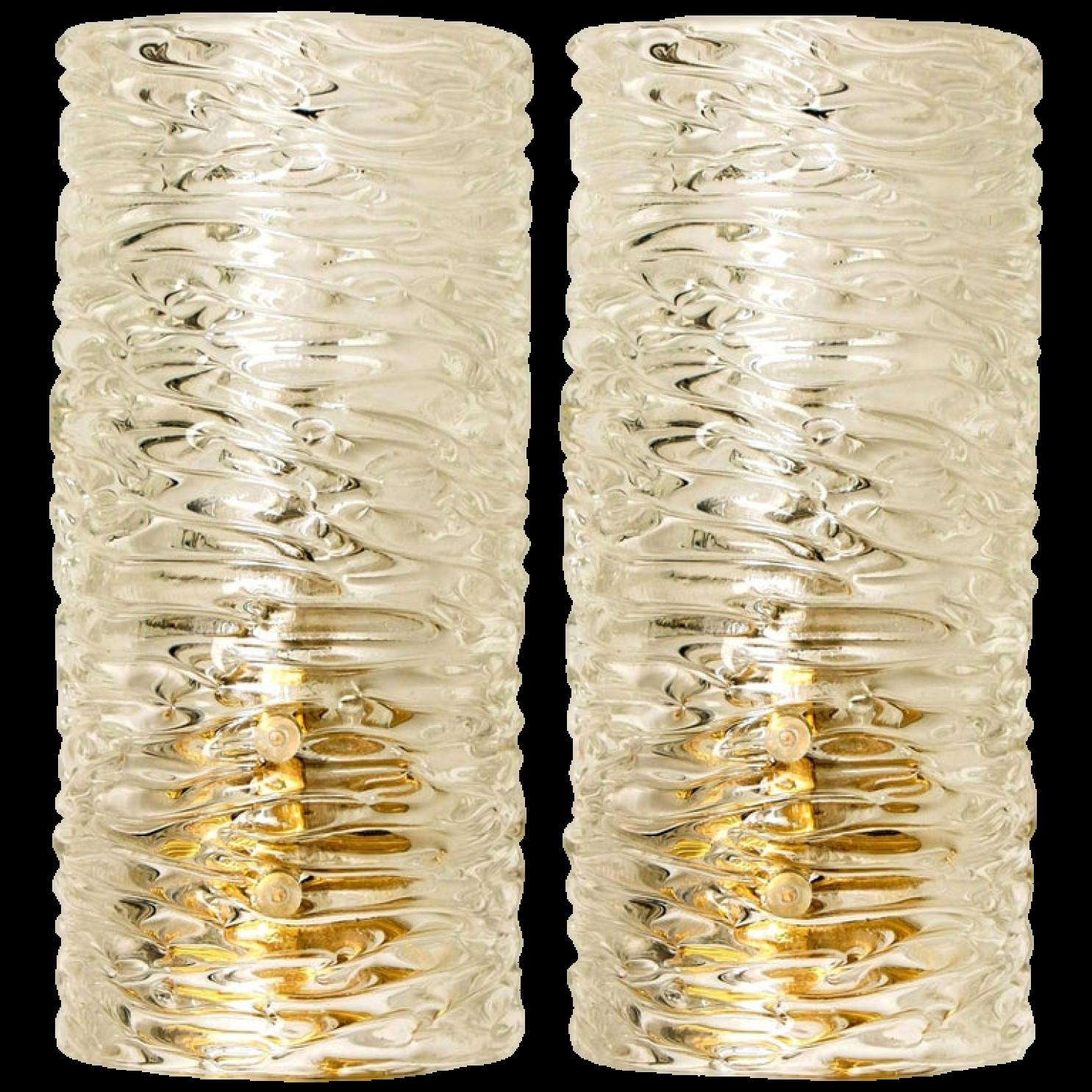 Two wall lights by J.T. Kalmar, Vienna, Austria, manufactured in circa 1960. This pair is handmade and high end. Each wall light has a half round wave textured glass shade with a brass back plate,

The wave texture gives a nice diffuse light effect