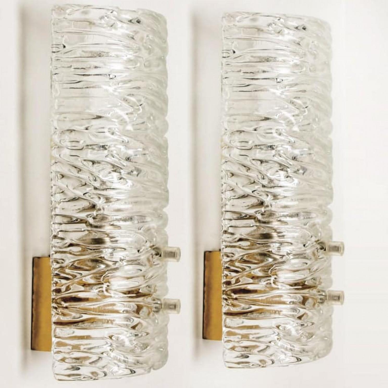 Two wall lights by J.T. Kalmar, Vienna, Austria, manufactured in circa 1960. This pair is handmade and high end. Each wall light has a half round wave textured glass shade with a brass back plate,

The wave texture gives a nice diffuse light effect