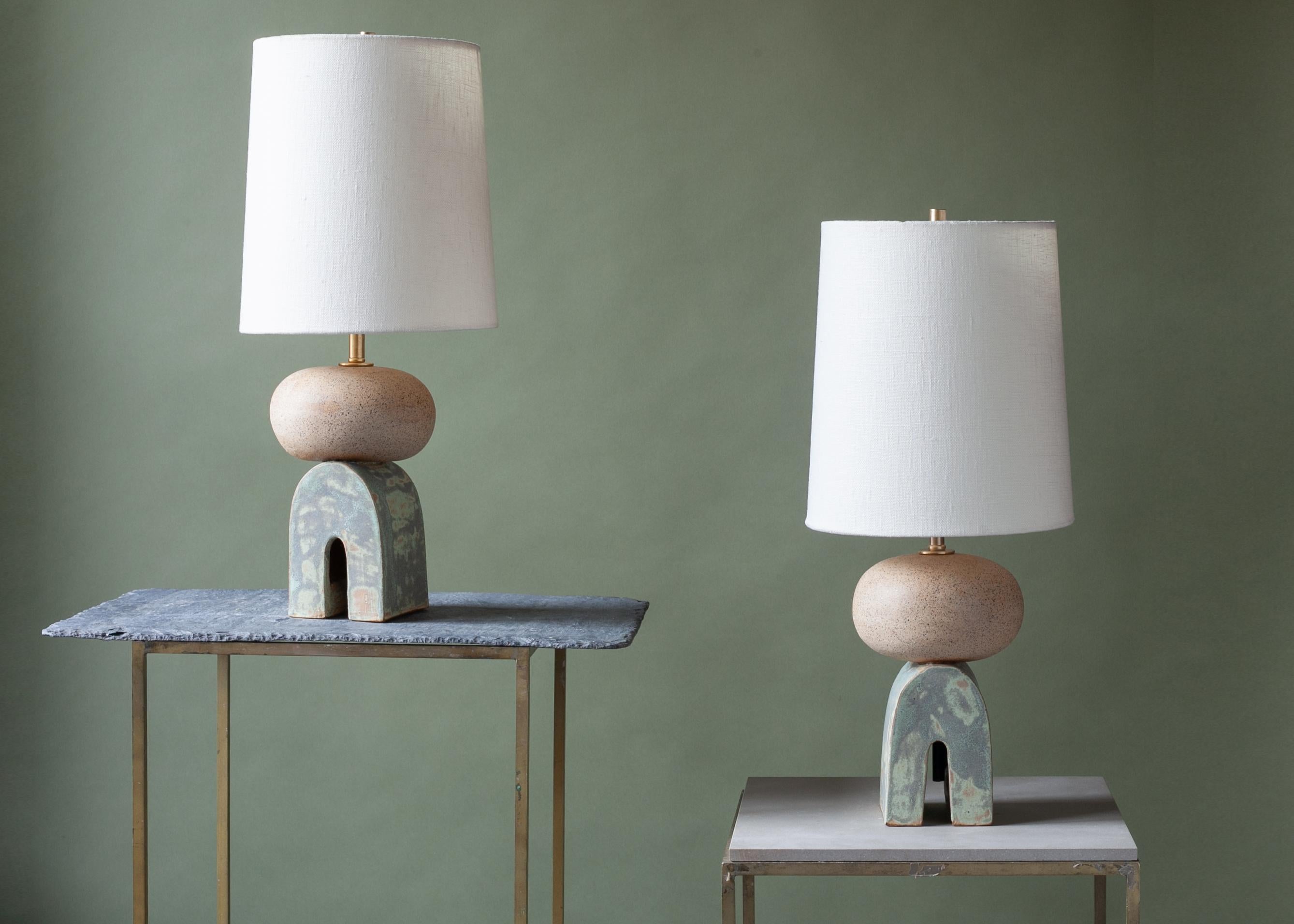 One of a kind, pair of ceramic lamps, thrown on the potters wheel and assembled by hand. The lamp base is comprised of two different clay bodies, with white underglaze and coppery green glaze. This piece was inspired by seashells and smooth stones