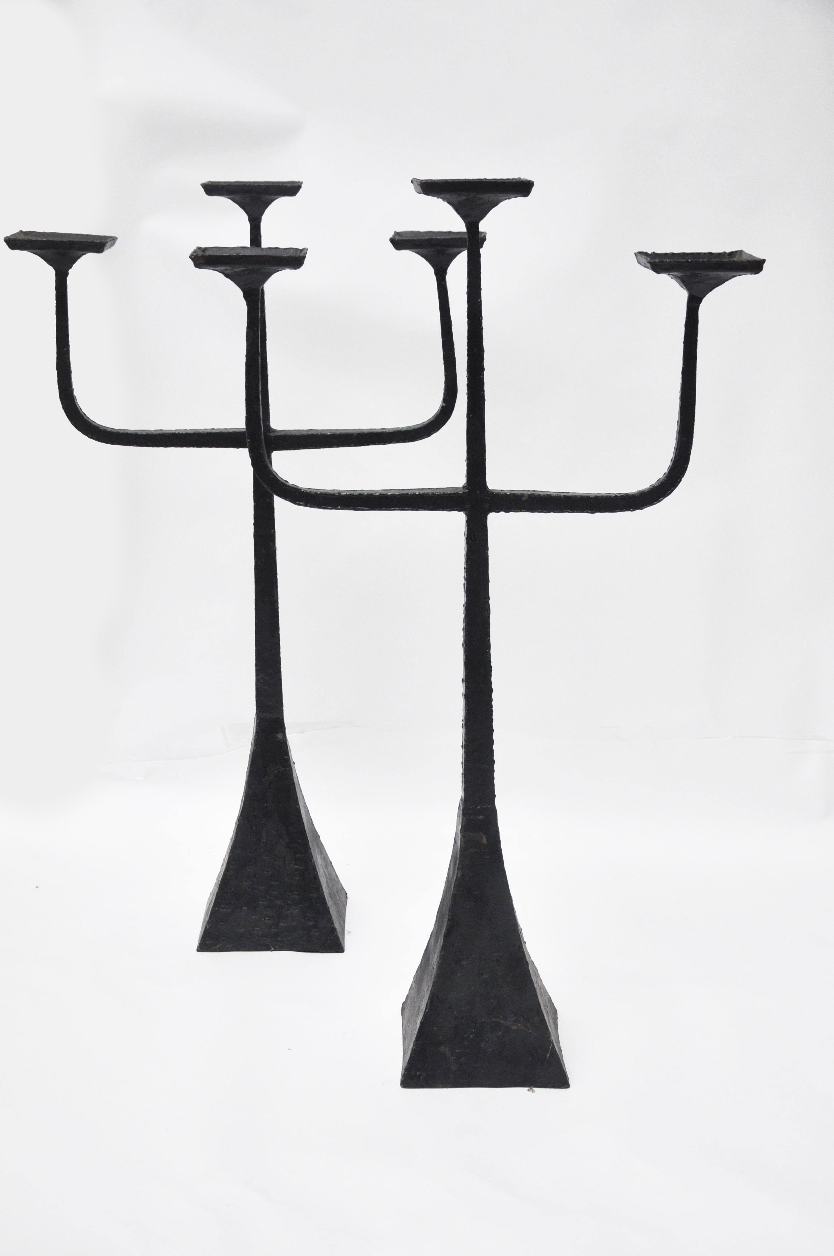 These floor candelabras are handmade of metal. The metal candelabras are painted black. Large pillar candles fit nicely on each of the platforms. The metal appears to be tapped and was not machine made. They are not identical in size due to the fact