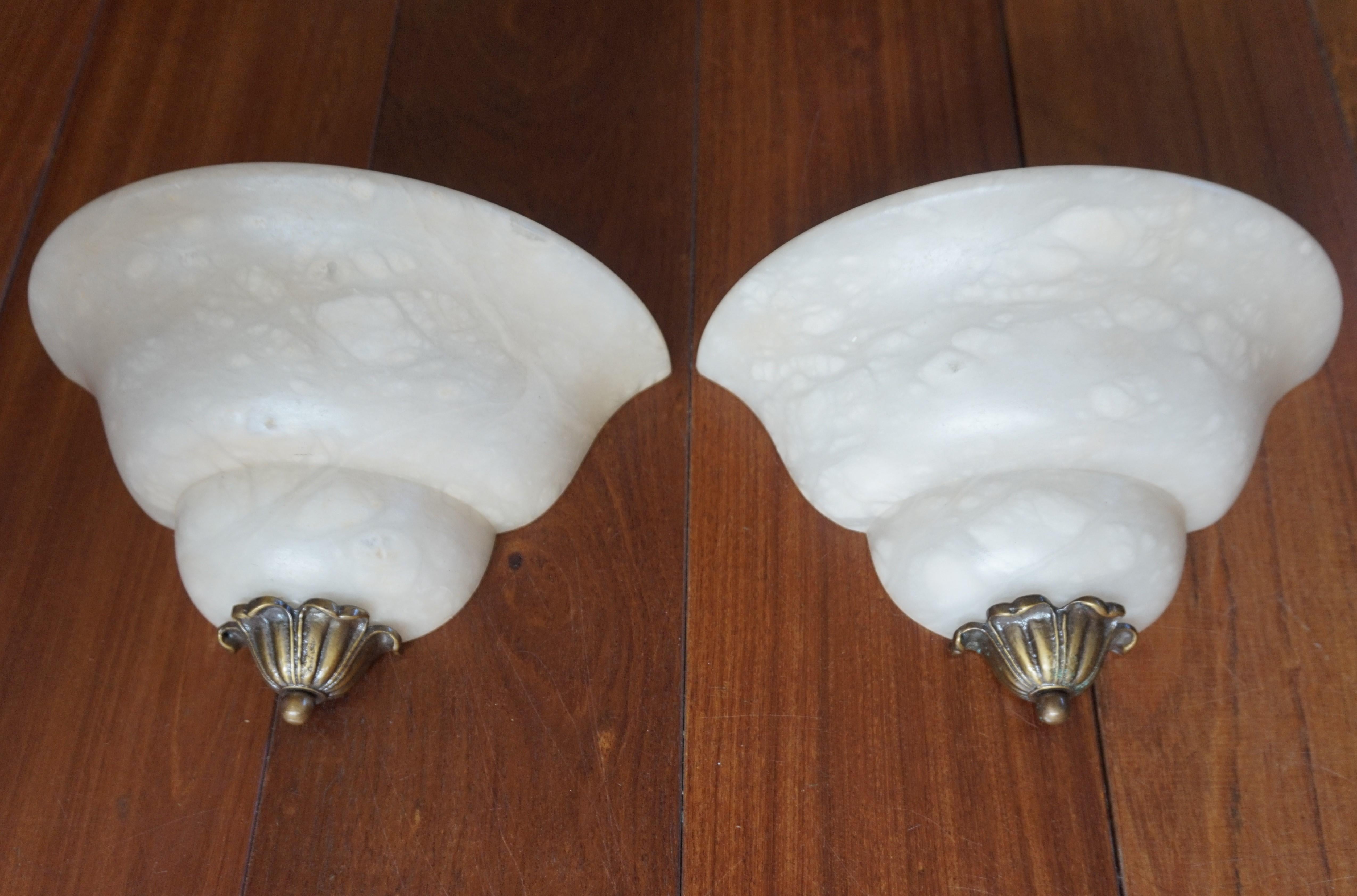 Excellent condition sconces with a marvellous 'cloud pattern' in the stunning alabaster shades.

This French pair of alabaster sconces is beautiful in shape and practical in size. Hand-crafted with a bronze bud at the bottom, these stylized Art Deco