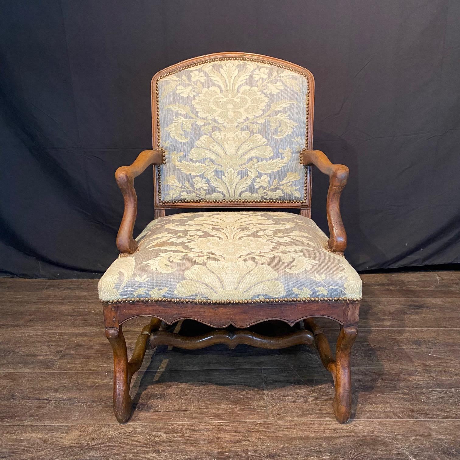 Elegante coppia di poltrone Luigi XIV risalenti all'inizio del XIX secolo, ciascuna delle quali poggia su gambe collegate tra loro da un cosiddetto 