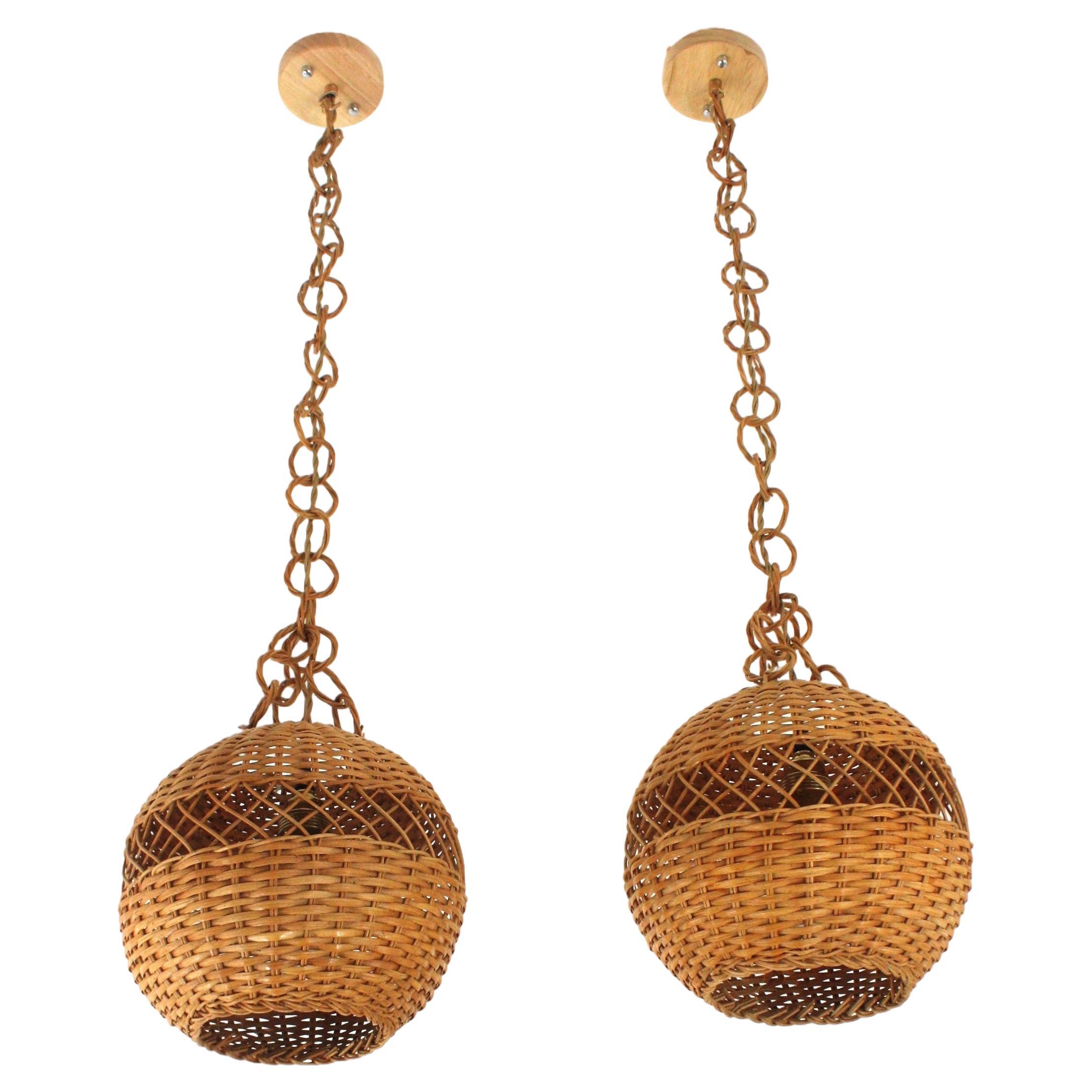 Eye-catching pair of handcrafted braided rattan / wicker pendant hanging lamps. Spain, 1960s.
This beautiful suspension lamps feature a hand-woven wicker globe shaped lampshade. They hang from a chain with braided rattan links ended by a wood