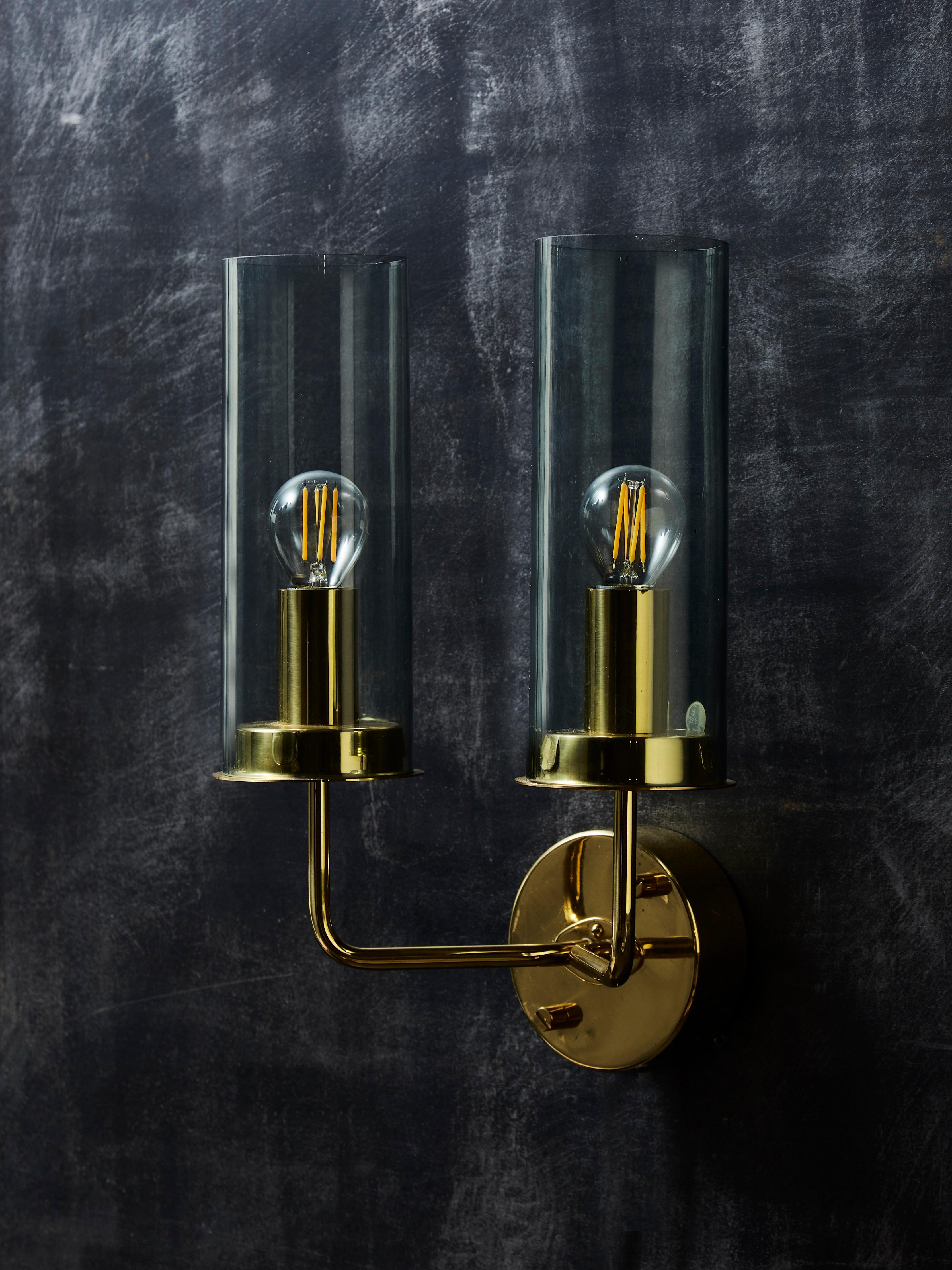 Pair of two lights Hans Agne Jakobsson wall sconces, made of brass structures and two lightly tinted glass shades.