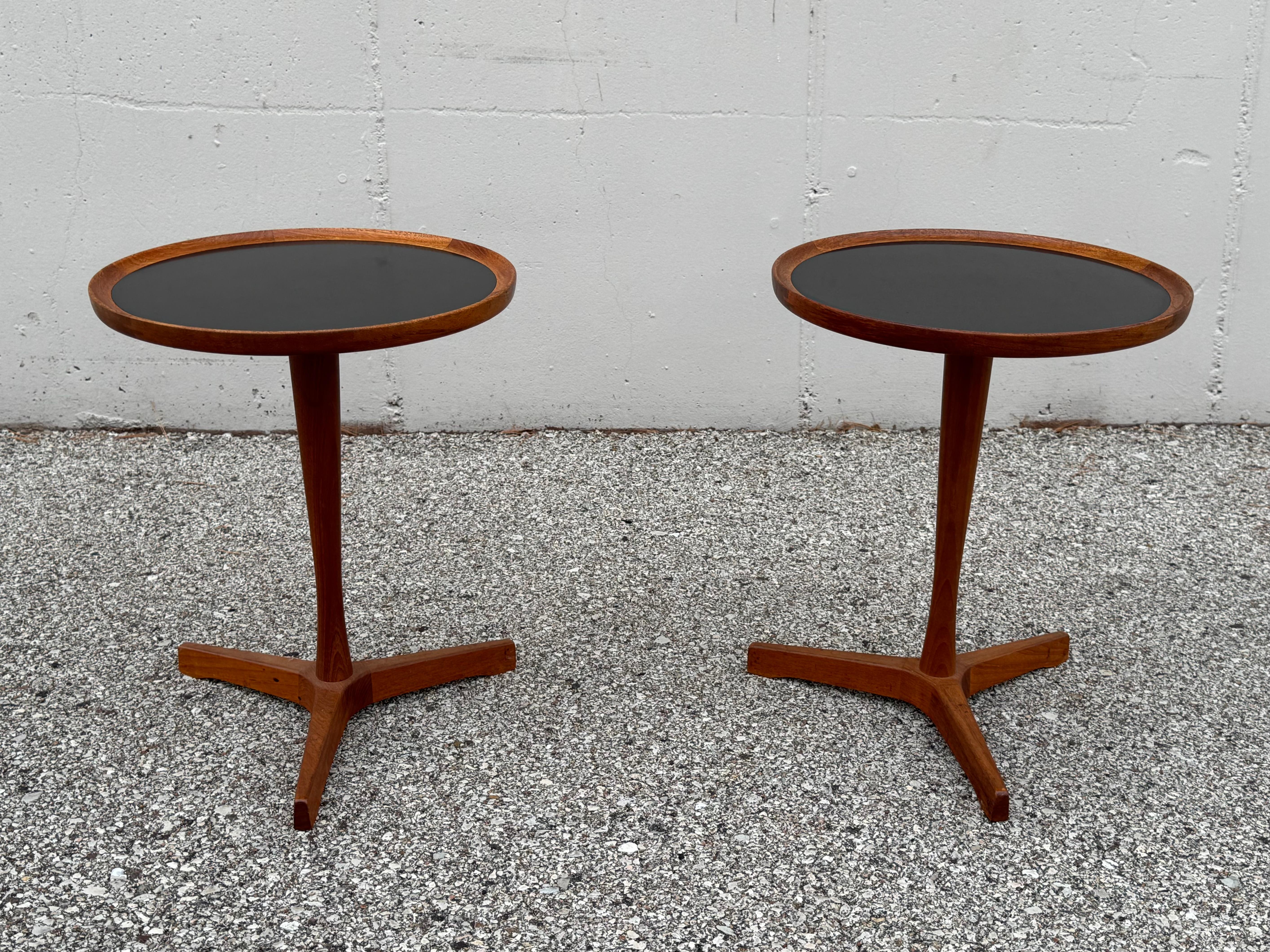 1960s Scandinavian Modern design at its best, simple but elegant. These matching pair of Hans C. Andersen tripod base teak side tables with round black laminate tops by Artex of Denmark. Marked on base, Designed by Hans C. Andersen Made in Denmark.