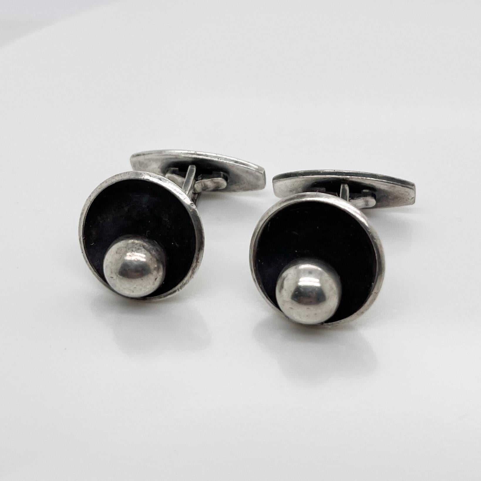 A very fine pair of Hans Hansen Danish Modern sterling silver cufflinks.

Model no. 610.

Each with a round silver ball that is set on the side of a silver bowl form. 

Simply terrific cufflinks from one of the Danish Modern masters!

Date:
20th