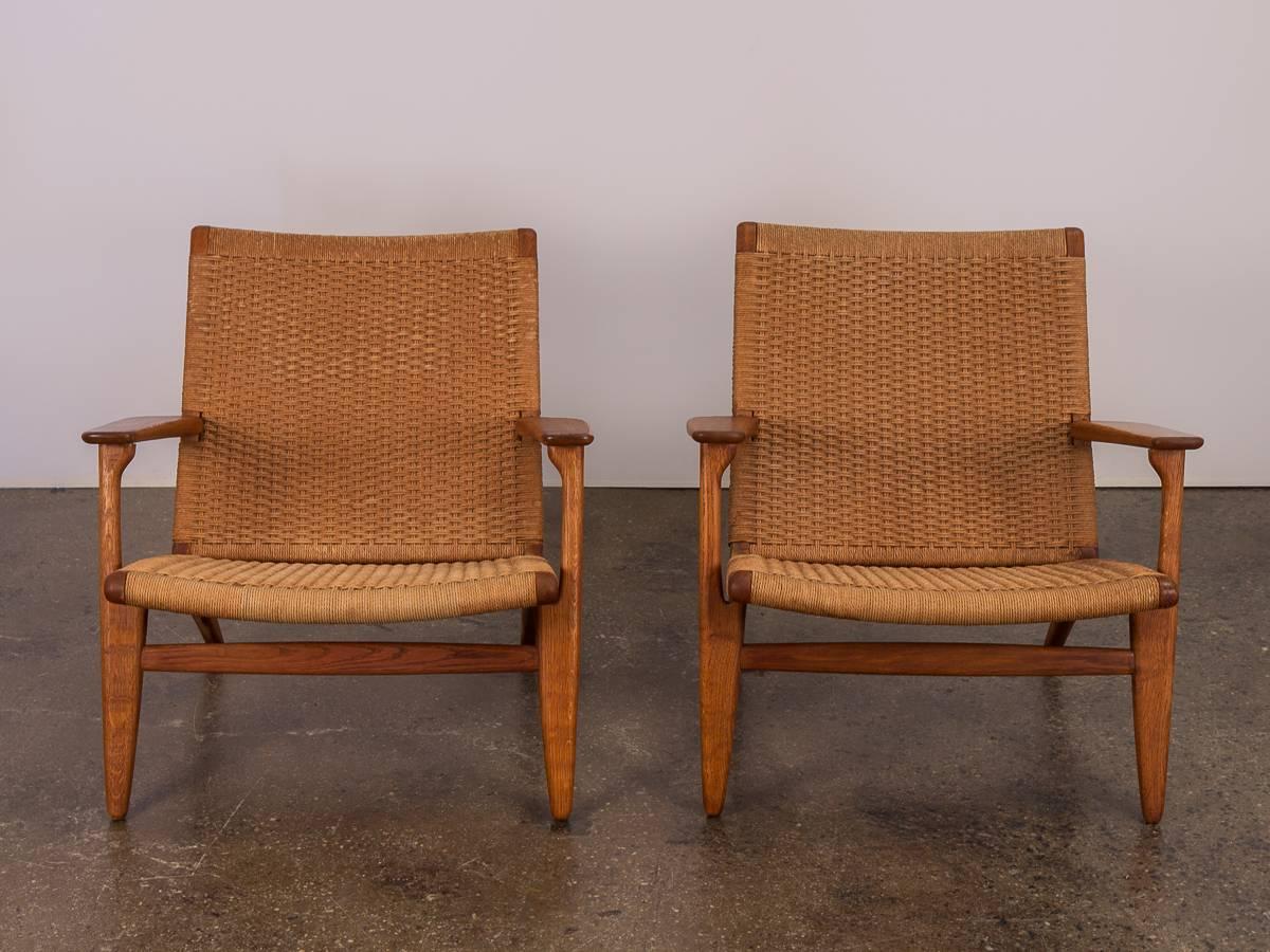Pair of 1950s Hans J. Wegner Ch-25 Armchairs for Carl Hansen & Son. An exceedingly comfortable, solid lounge chair. The personality of this design is characterized by the reclining silhouette and handwoven papercord seats and backs. Wide armrests