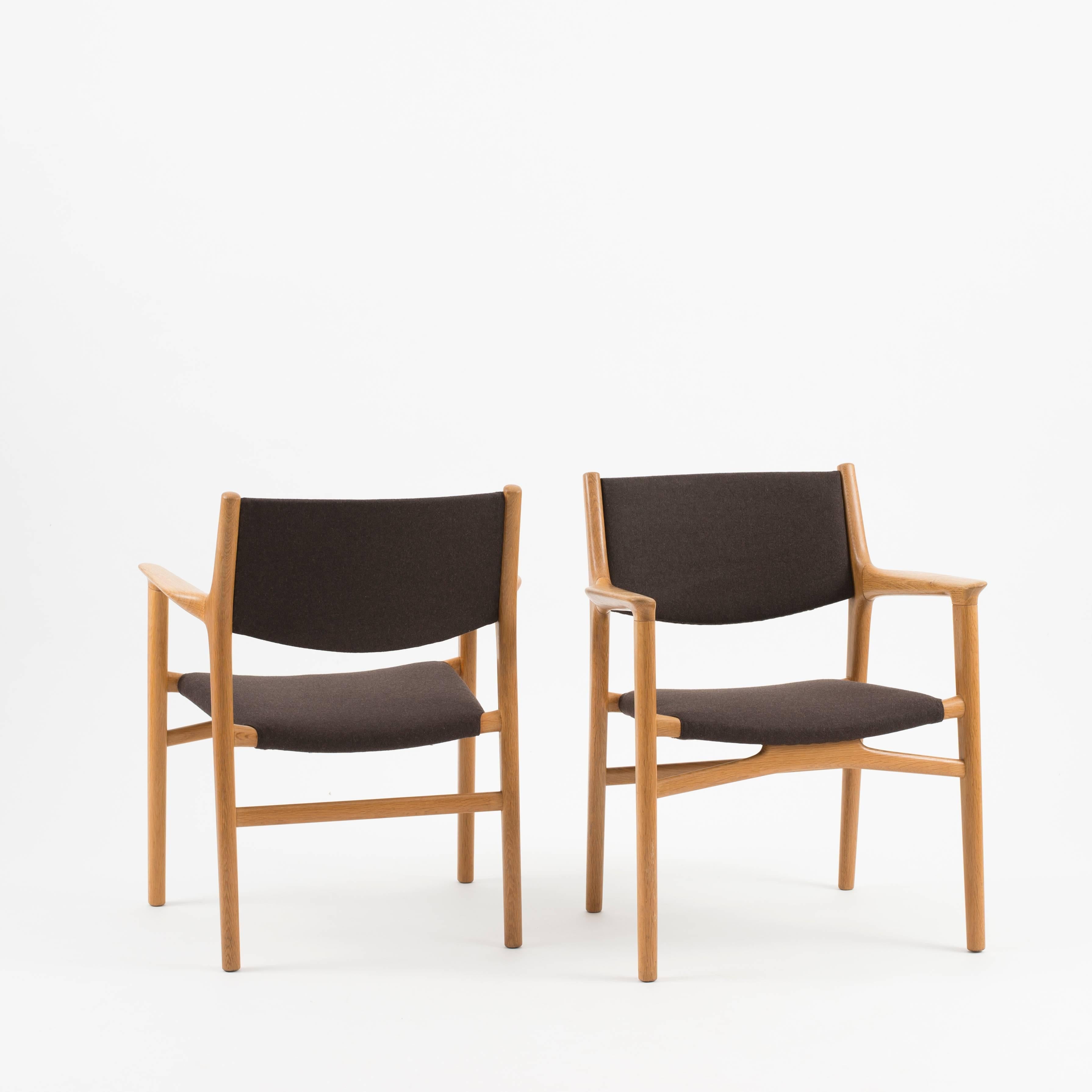 Hans J. Wegner model JH 515. A pair of oak armchairs. Seat and back upholstered with brown felted wool. Executed by cabinetmaker Johannes Hansen, Denmark.