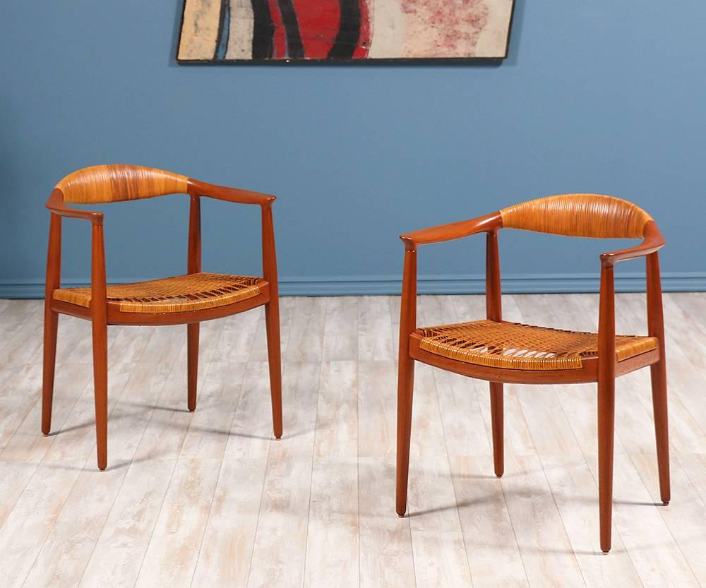 A pair of caned ‘Round’ chairs designed by Danish craftsman, Hans J. Wegner, for cabinetmaker Johannes Hansen in Denmark circa 1940’s. Internationally known as “The Chair,” Wegner’s design features a curved solid teak top rail with serrated joinery