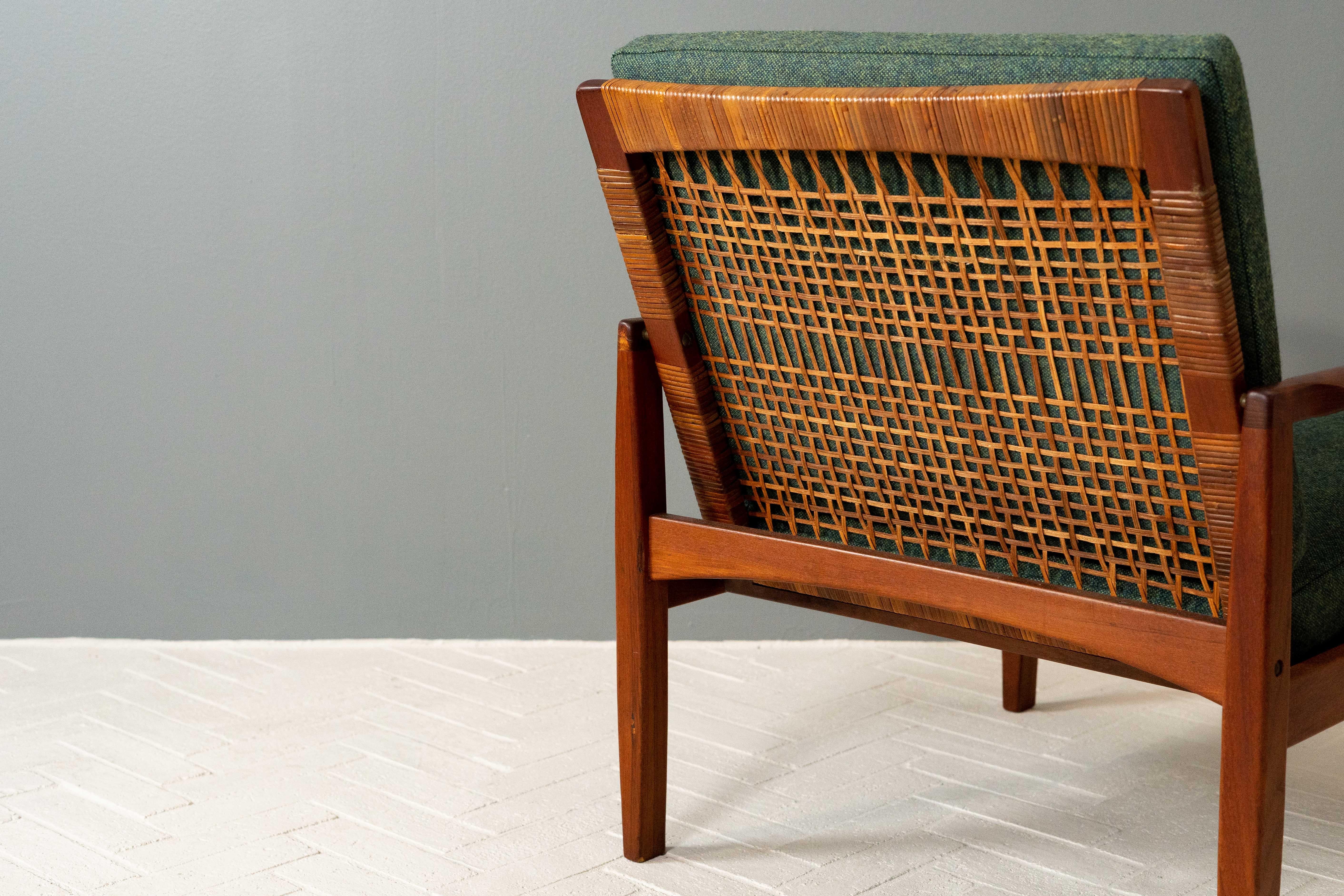 Denmark, ca. 1950s. A stylish pair of lounge chairs by Hans Olsen for Juul Kristiansen. Each features a solid teak frame with handwoven cane back. Reversible seat and back cushions are freshly covered in a pleasing (and soft) dark green wool from