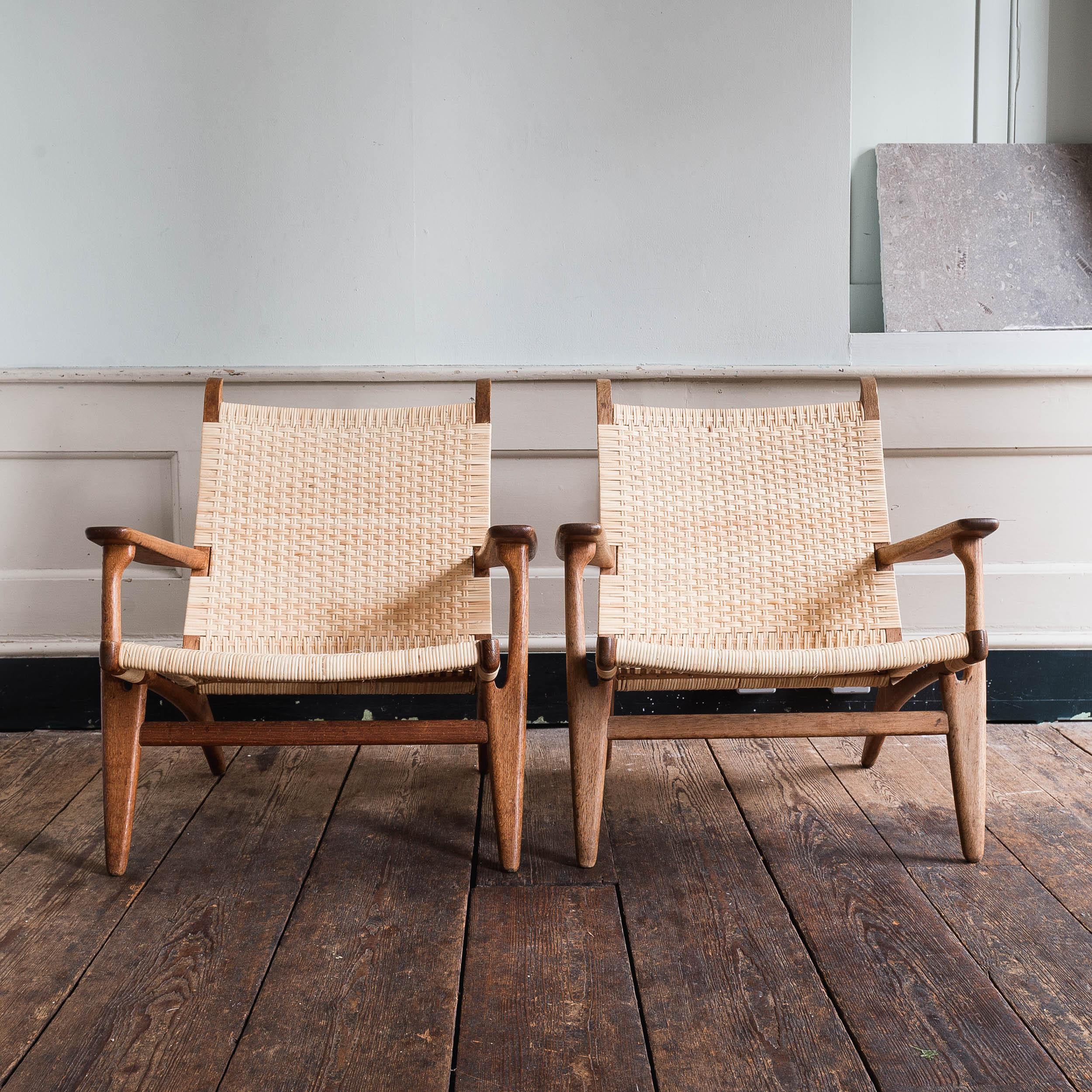 Pair of Hans Wegner CH 27 easy-chairs, designed in 1951, manufactured by Carl Hansen & Son, Denmark.

Oak frames, seat and backrests re-caned to the original specification. 

Rare pair of early 1950s examples of the model. Chair frames in