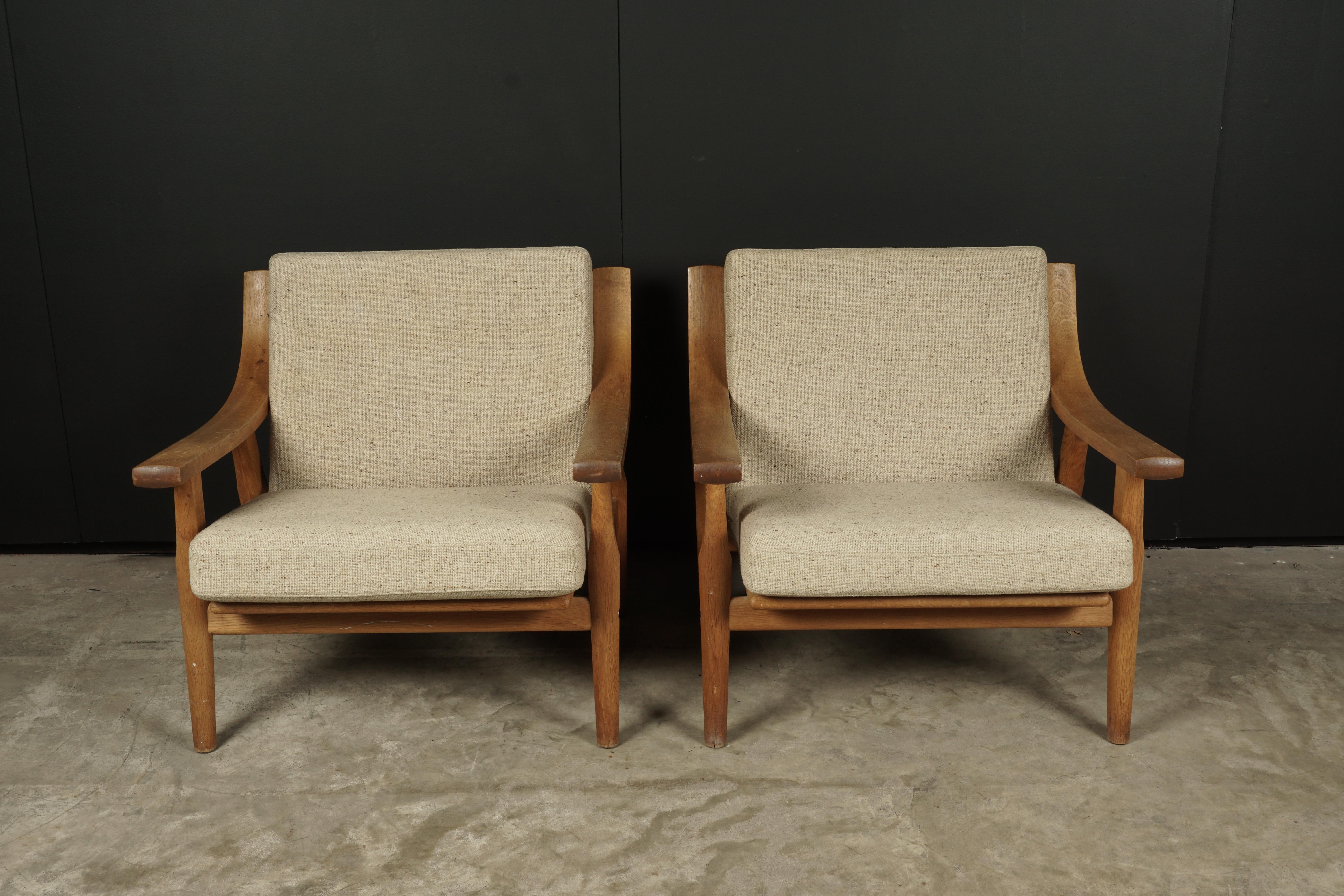Vintage pair of Hans Wegner lounge chairs, Model GE-530, from Denmark, circa 1960. Solid oak frame with original upholstery.