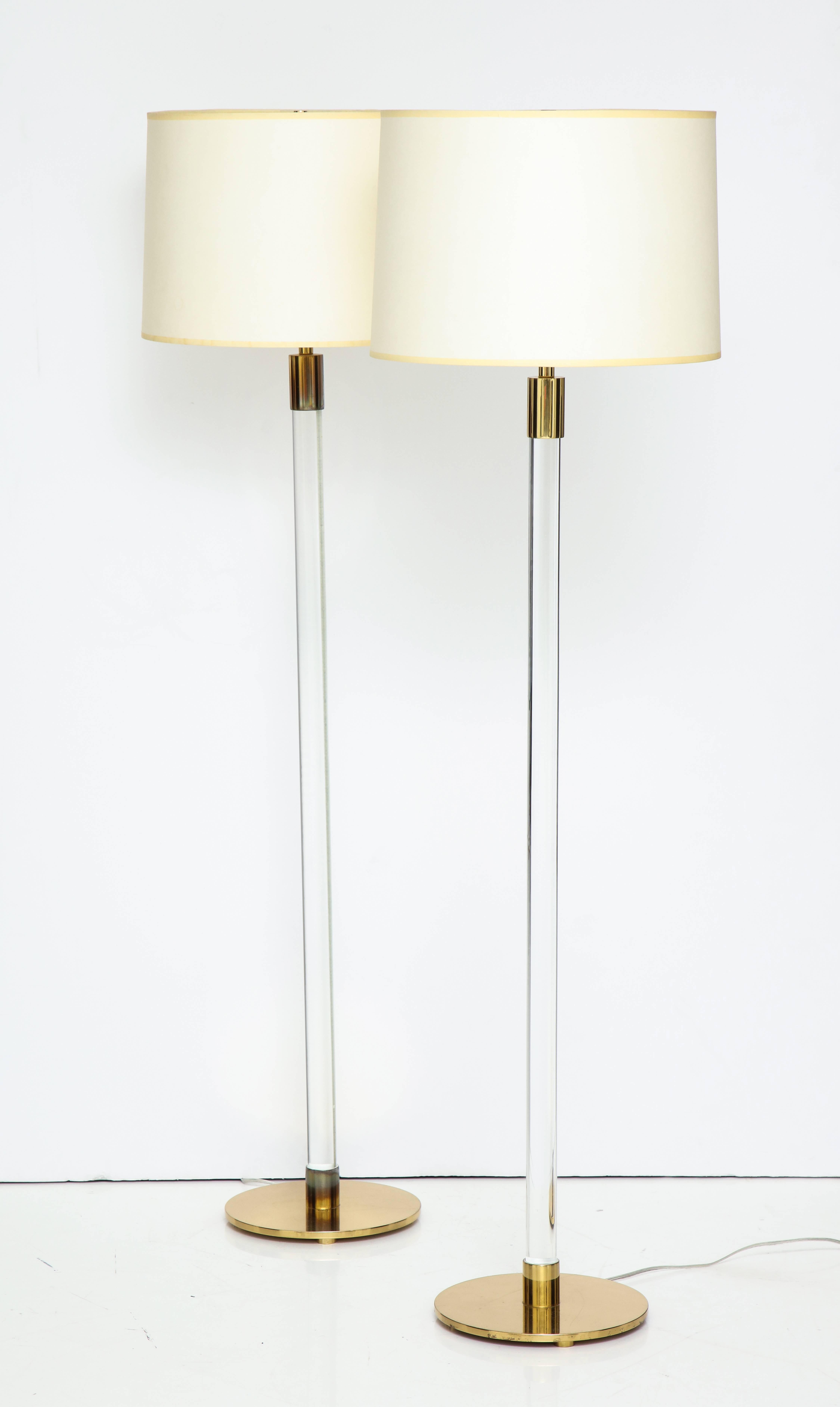 Pair of brass and glass floor lamps with the less common round disc base. Made by Hansen, circa 1970s. The cord runs in a channel up the back of the glass columns, and is invisible from most angles. With recent shades. Both with Hansen marks