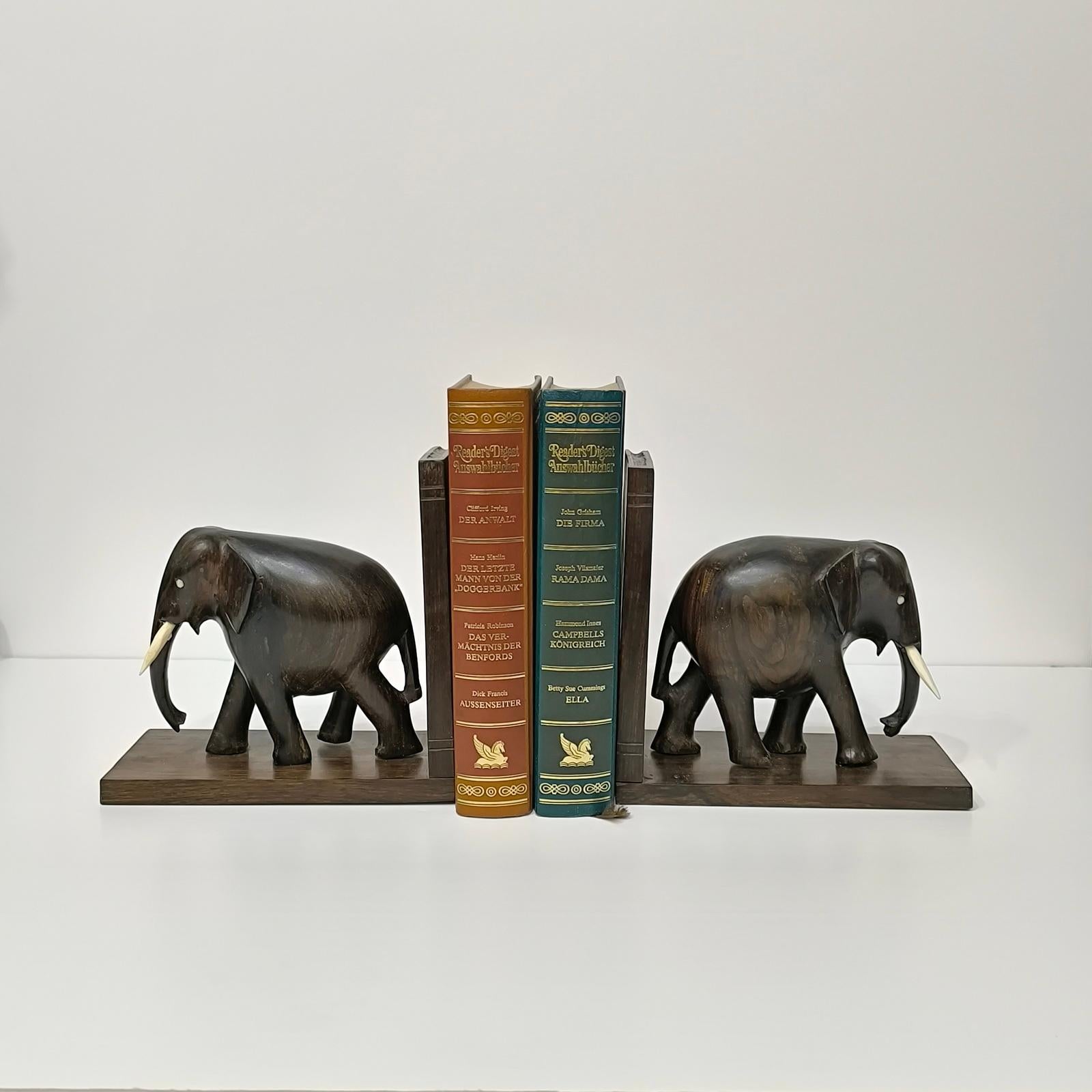 Il s'agit d'une paire de serre-livres éléphants vintage. Ils sont fabriqués en bois dur, sculptés à la main, et ont des yeux et des défenses en os. 

Ils sont en excellent état d'usage. Ils sont ravissants pour le lecteur régulier de romans, sur un