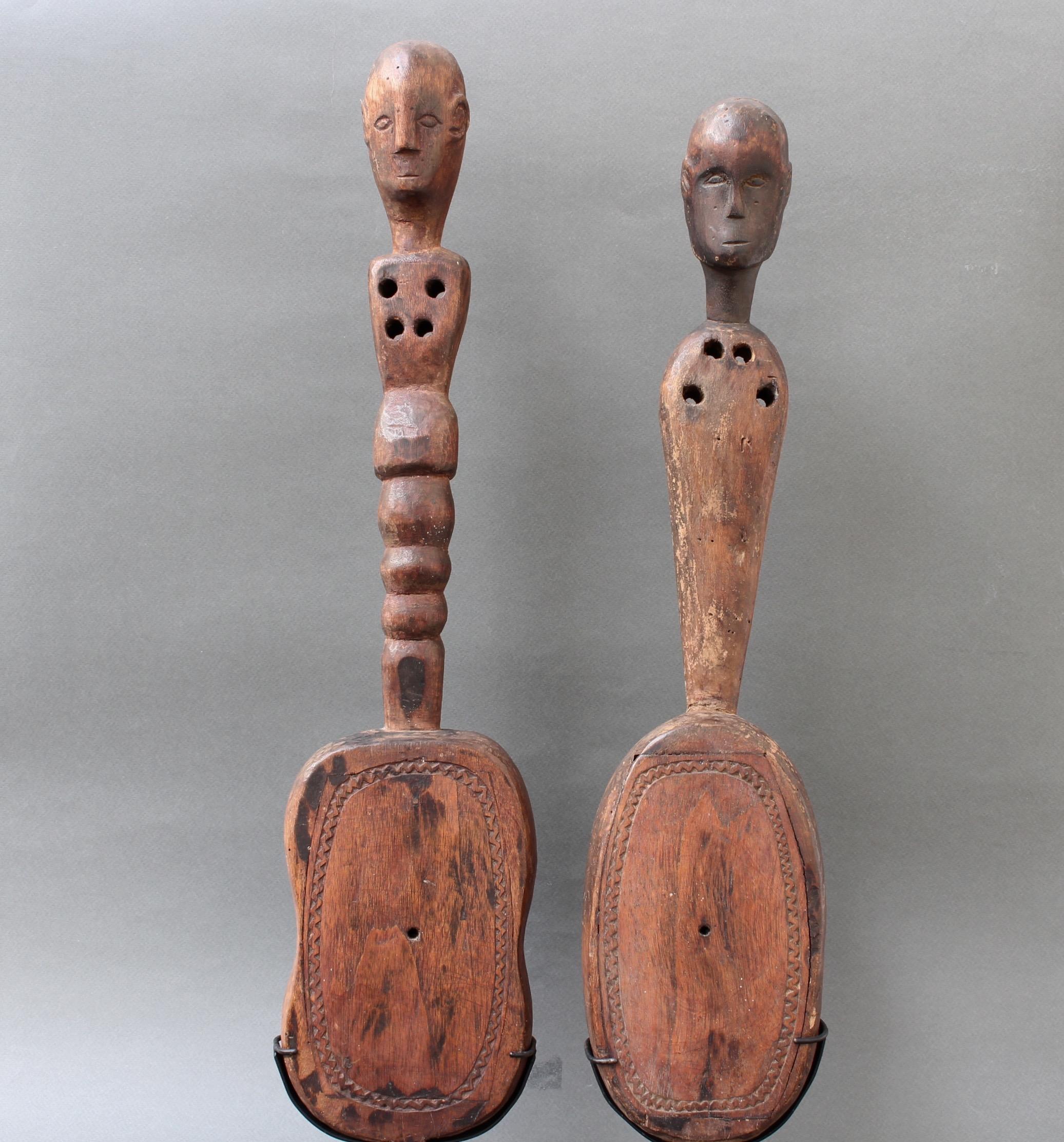 Pair of hardwood lutes from Sumba Island, Indonesia, with anthropomorphic figures (circa early 20th century) on modern metal stands. Music played on these instruments is closely tied to ritual and ceremony. Unusually, this instrument overlaps in the