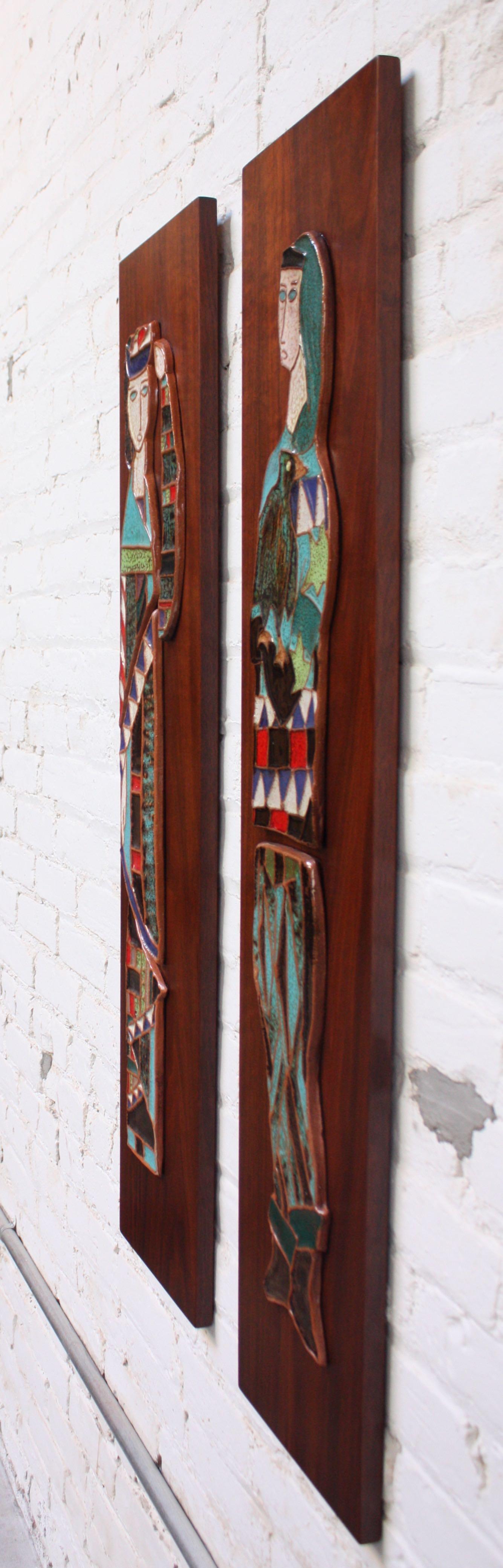 Pair of Harris Strong, circa 1960s, Bronx, NY glazed ceramic tiles depicting two harlequin figures mounted to walnut plaques. 
Bold colors are further enhanced by the vivid grain / dark tone of the walnut panels. 
Excellent, vintage condition with
