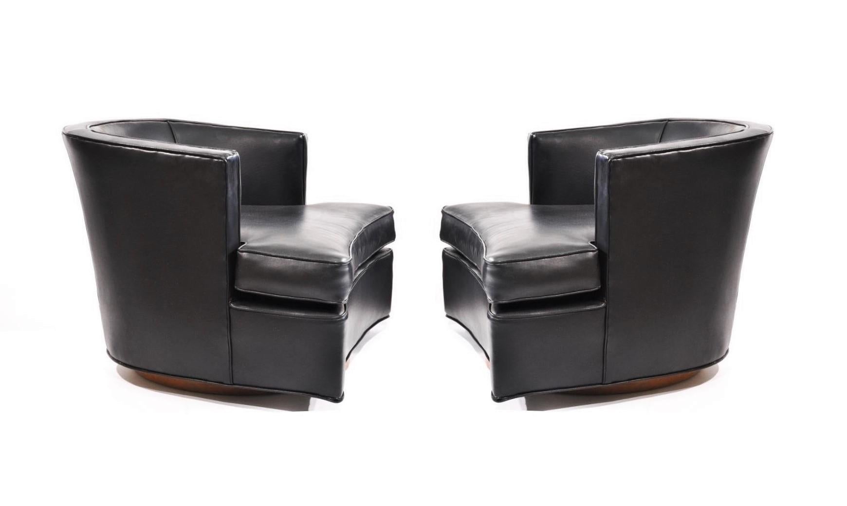 Mid-Century Modern comfortable pair of swiveling lounge chairs designed by Harvey Probber, Model 303A. The chairs professionally re-covered in a black leatherette upholstery with decorative nails lining the corners on swivel bases in oakwood.
