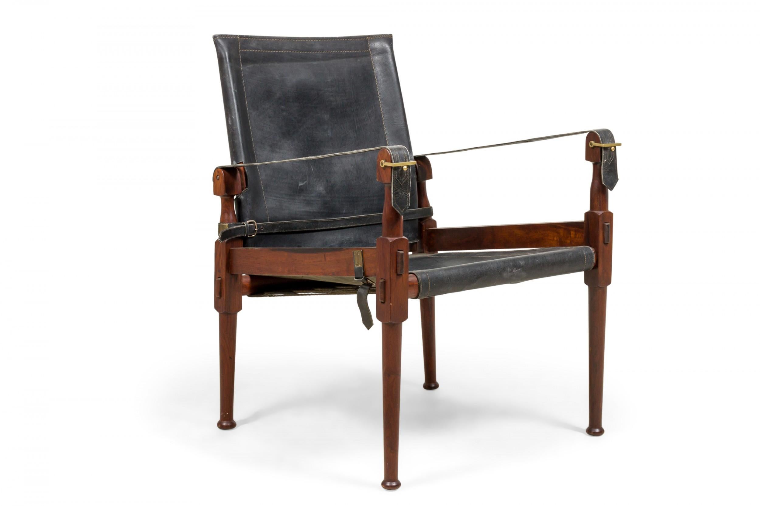 Pairof Pakistani mid-century 'Roorkee' safari campaign chairs with carved walnut frames and black leather sling seats, backs and arms that collapse down to a portable form. (M. Hayat & Bros Ltd.).
 
