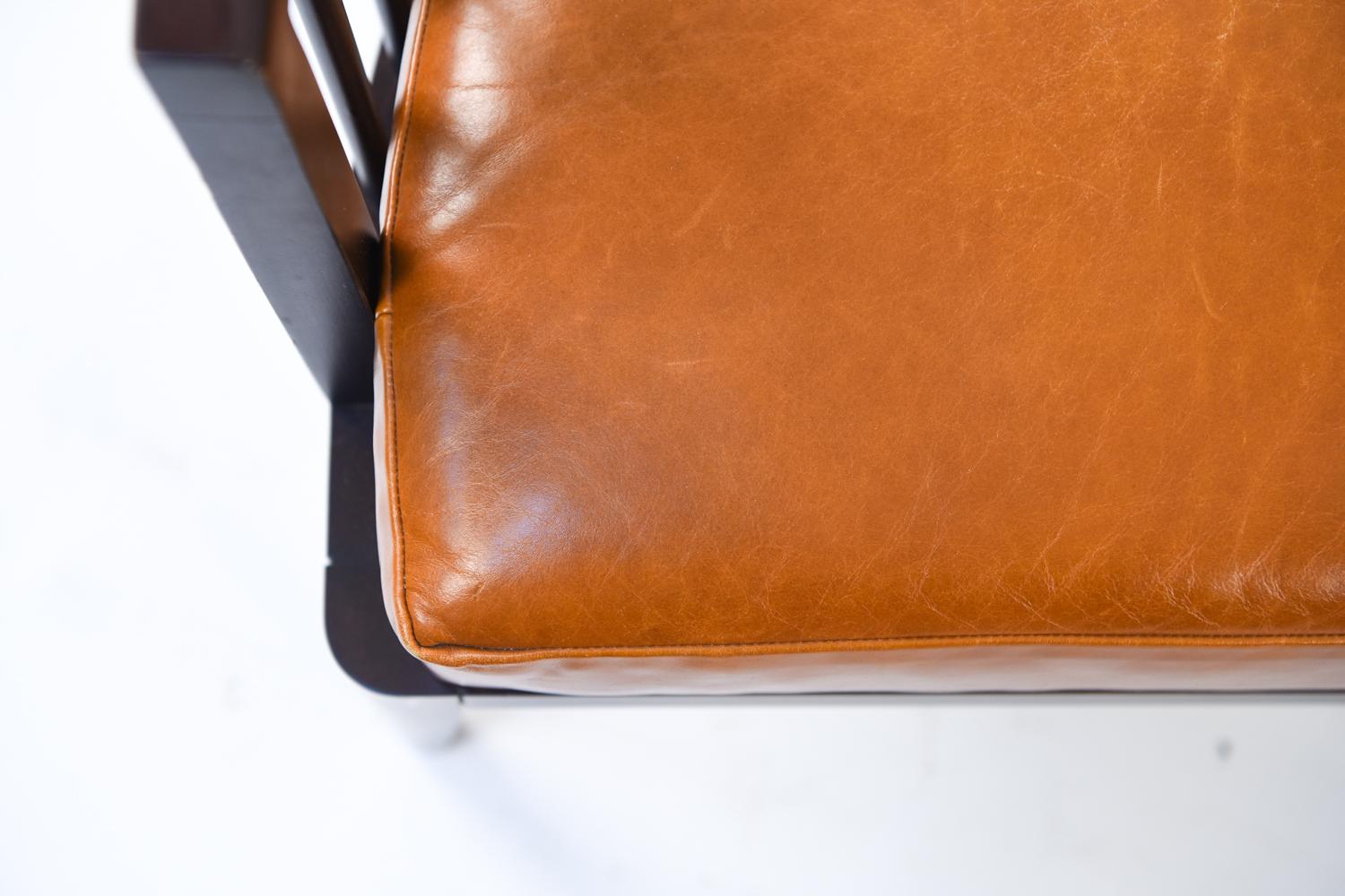 This attractive pair of spindle back lounge chairs are by HBF, as tagged underneath. With sturdy frames, tasteful orange cushions, and a modern design, this pair would be an eye-catching addition to an interior living space.