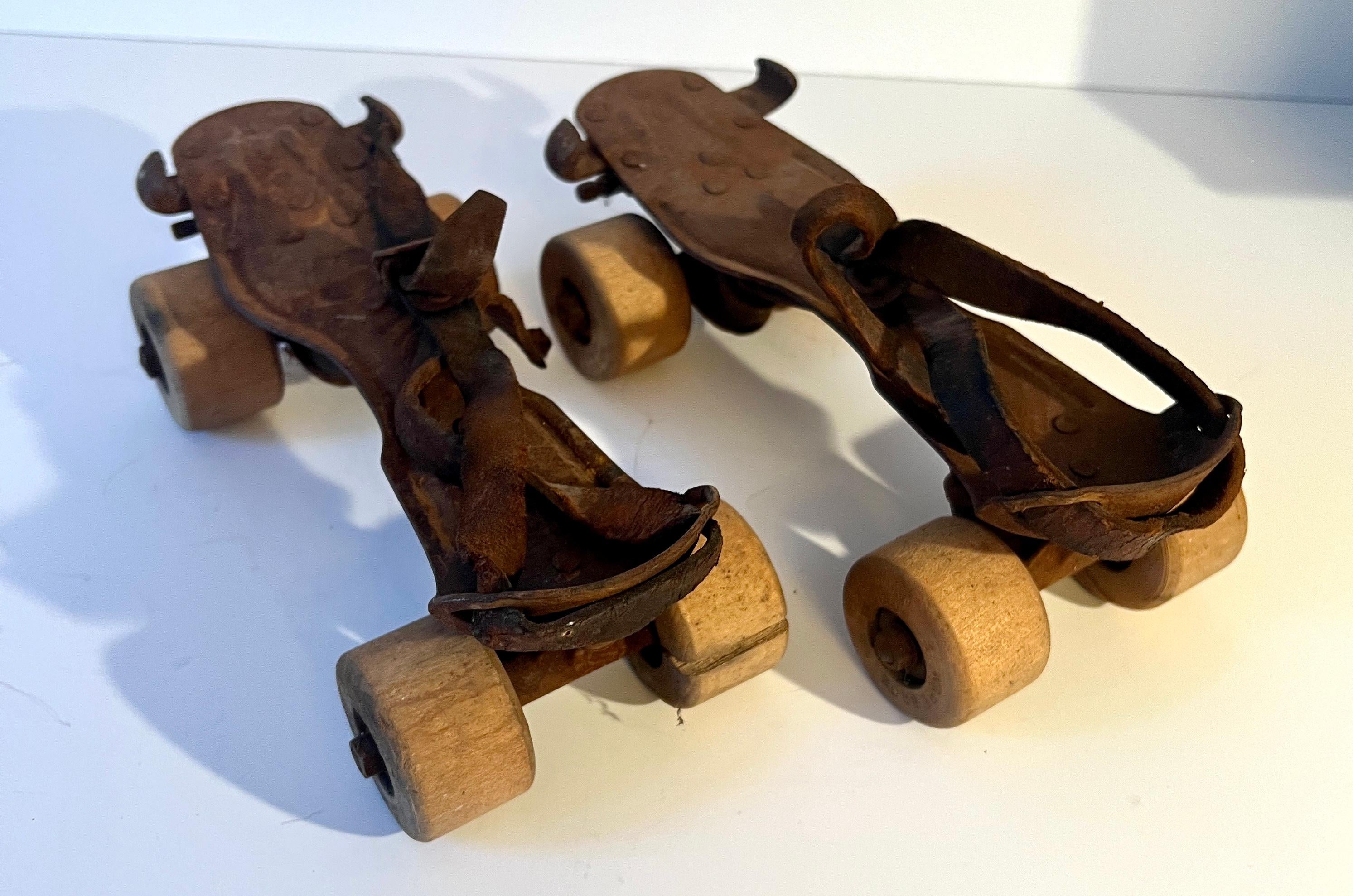 Une paire de patins à roulettes originaux en métal, fabriqués pour s'attacher aux chaussures afin de devenir des patins.  Les pièces sont fortement patinées et il reste quelques vestiges de la reliure en cuir.  Les roues en bois sont intactes.

Un