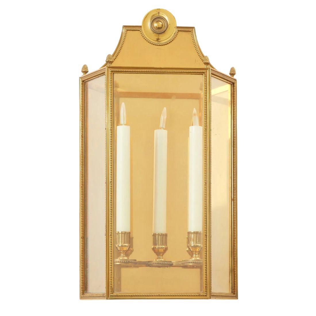 Paire d'appliques murales dorées à trois lumières.  Chaque applique est composée de trois panneaux en verre à l'intérieur desquels se trouvent trois lampes à bras de bougie. Les coins de chaque panneau sont finis avec des détails de perles et des