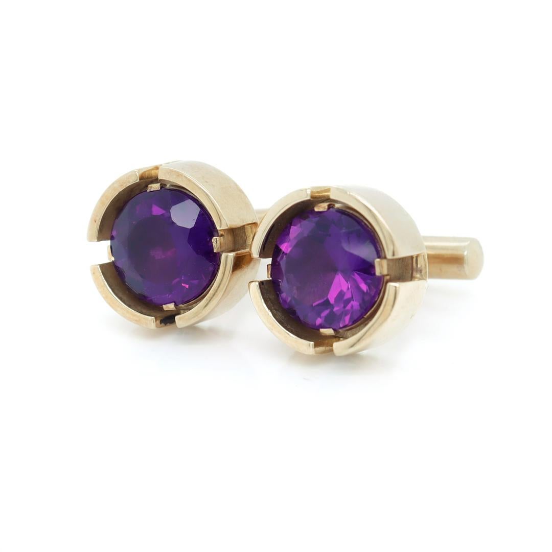 A fine pair of Mid-Century modern cufflinks.

In 14k gold.

Each with large round cut amethyst gemstones prong set in rivet-like heavy gold settings. Each set with thick posts and pivoting bullet toggles.

Simply a wonderful pair of Mid-Century