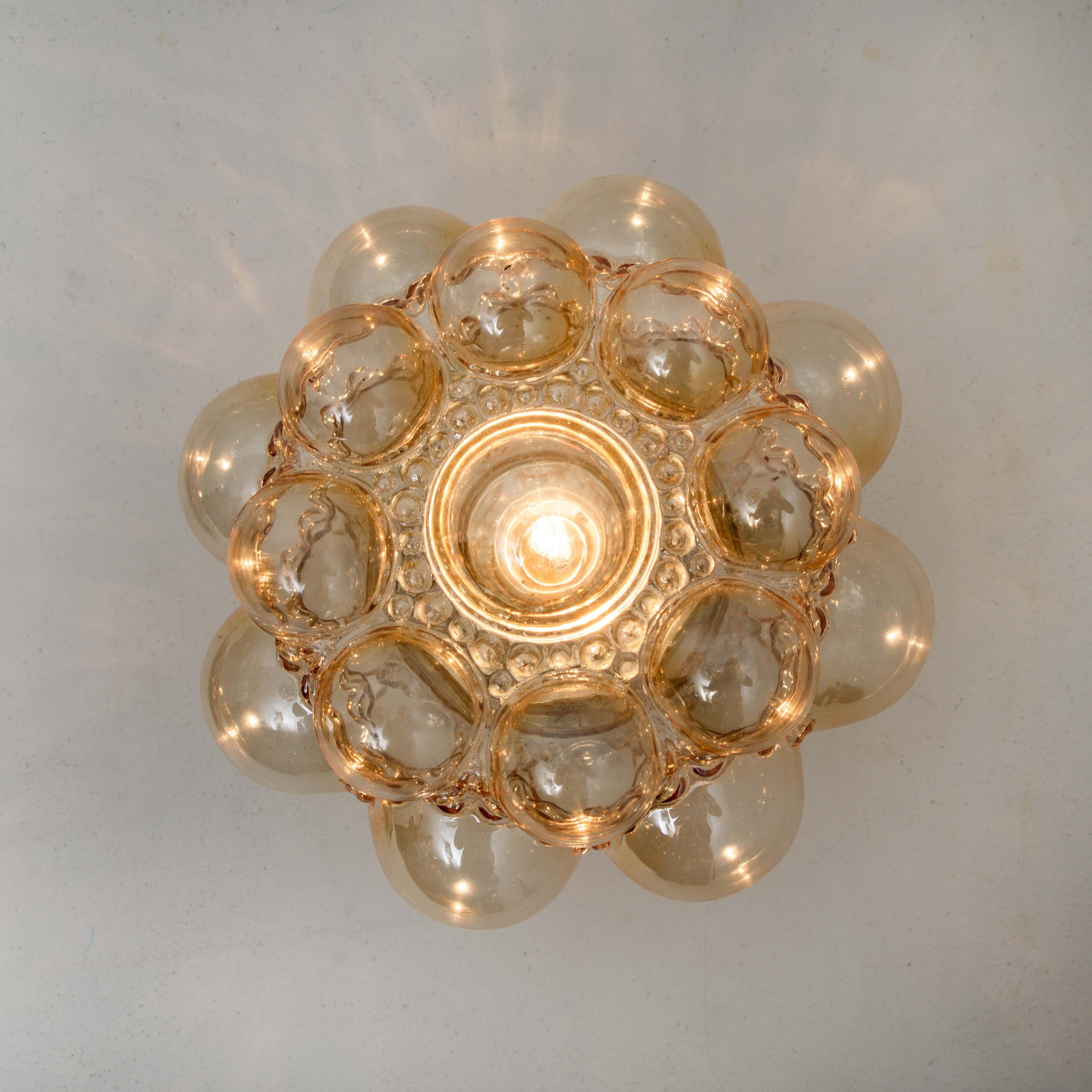 Beautiful high-end large bubble wall lights or flush mounts by Helena Tynell for Glashütte Limburg, Germany, 1960s.
Made of glossy amber colored glass with a brass colored base. A design Classic, the hand blown amber toned glass gives a wonderful