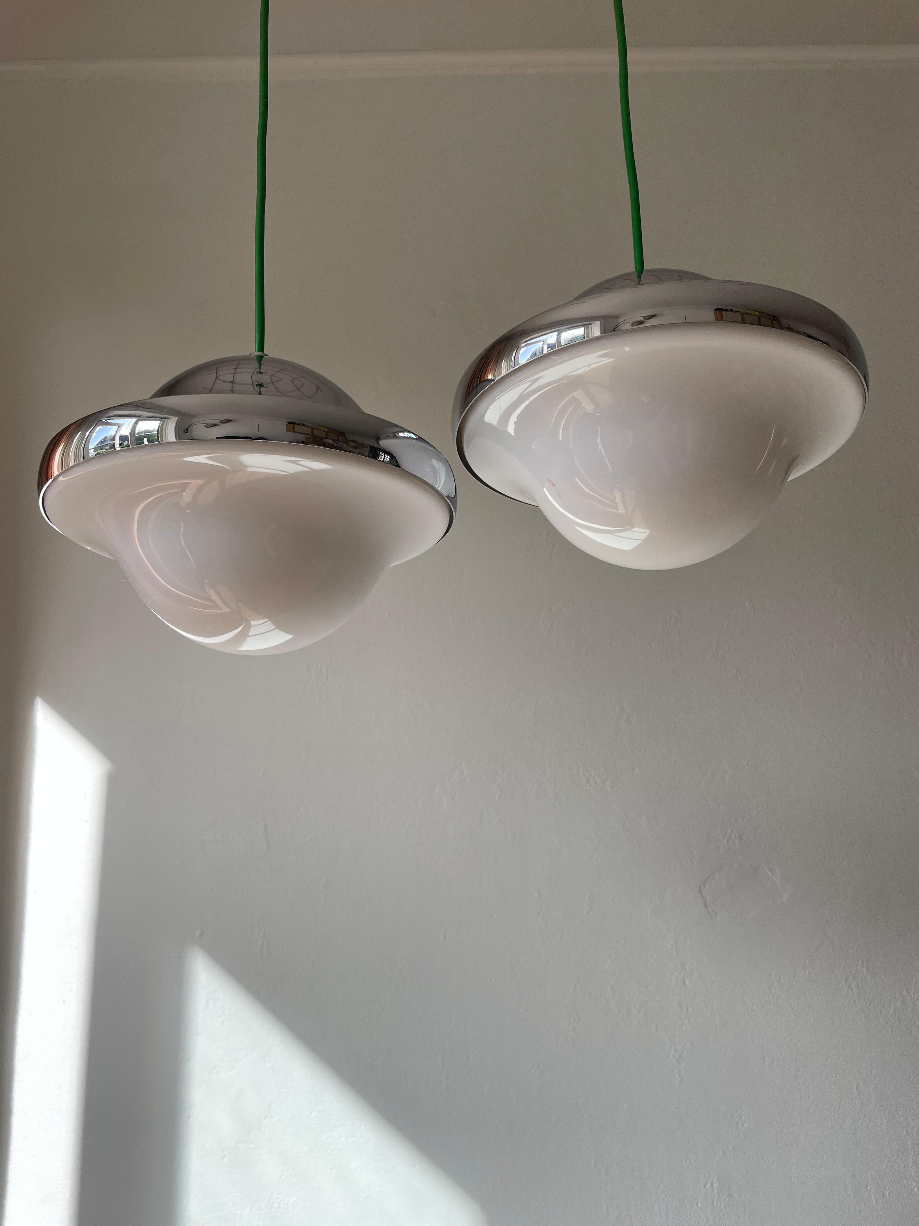 Une paire de l'un des designs les plus emblématiques de Henning Koppel, la lampe Bubi. Deux lampes Bubi en chrome brillant et acrylique blanc mat avec un cordon vert saisissant, conçues en 1972 par Henning Koppel (1918-1981). La forme circulaire,