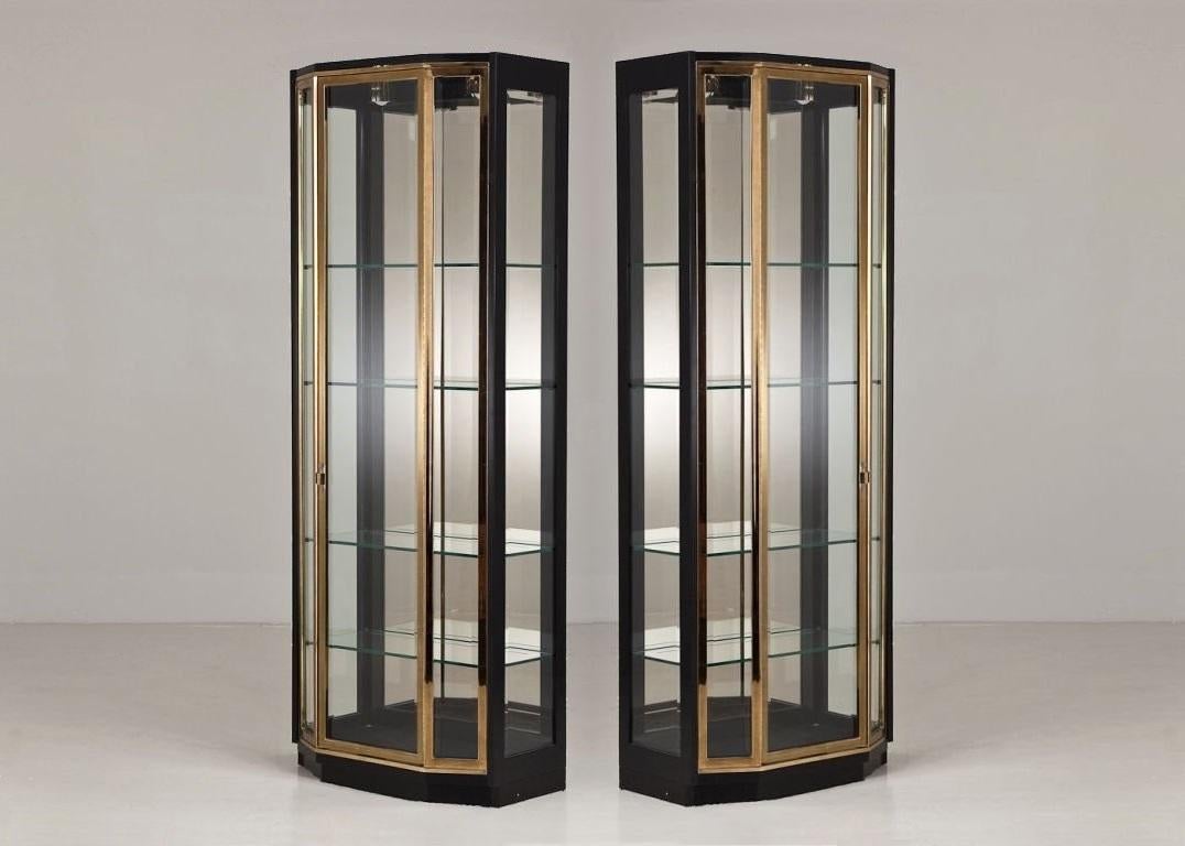 Exceptional pair of tall 1970s black lacquer and brass vitrines by Henredon. Featuring clean lacquered frames with brass trim on the doors. The cabinets feature beveled glass sides and doors that open to reveal four adjustable glass shelves,
