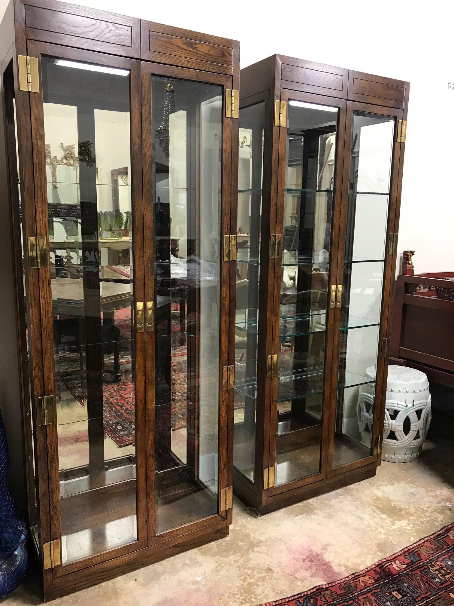 Gorgeous pair of Henredon china display cabinets with beveled glass doors. Each cabinet includes four glass shelves with grooves in the back for standing plates. Brass detailing on door handles and hinges.